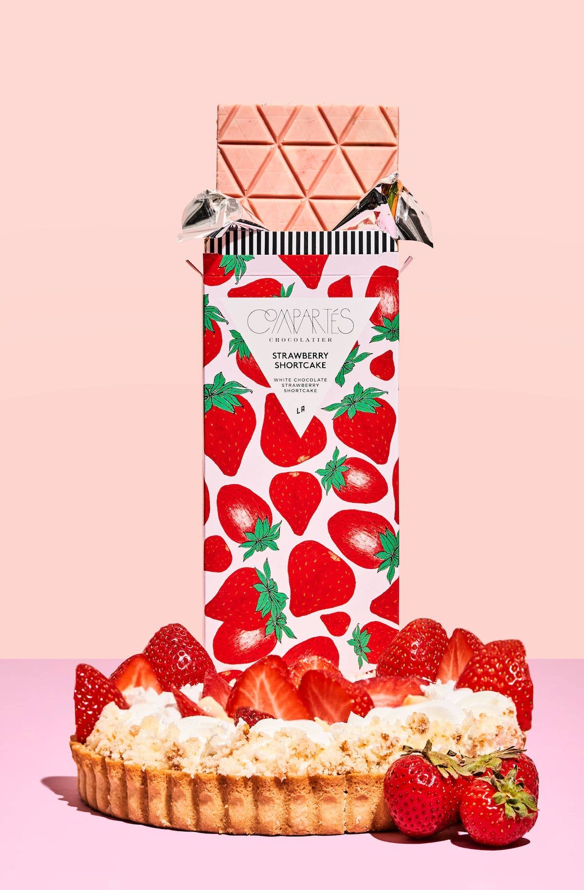 A chocolate bar with white chocolate chips and pieces of strawberry, presented in a bar with hand-drawn strawberry graphics.