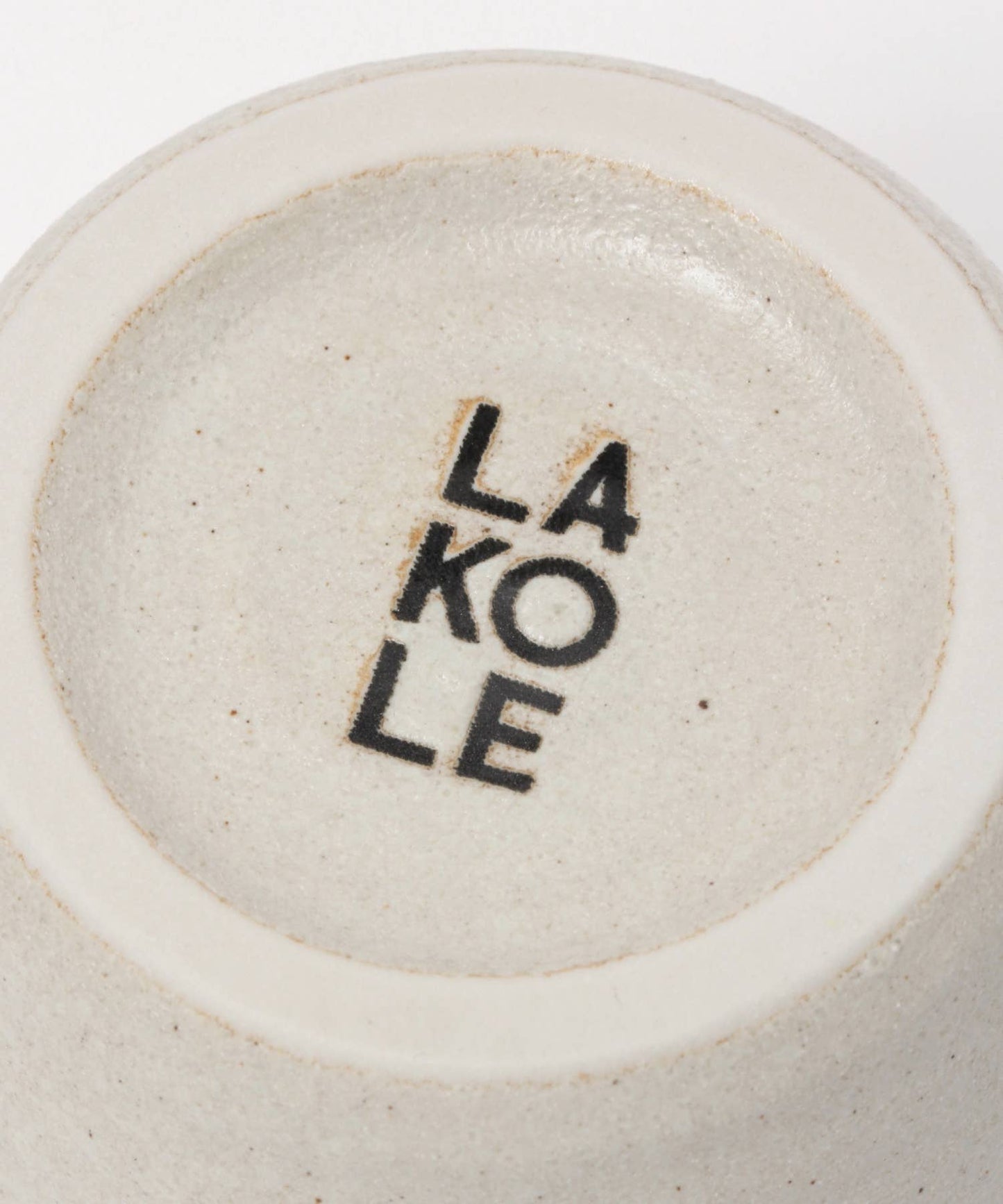 A white ceramic mino ware mug with an organic shape, seen from the bottom, on a white background. We can read "Lakole", which is the brand.