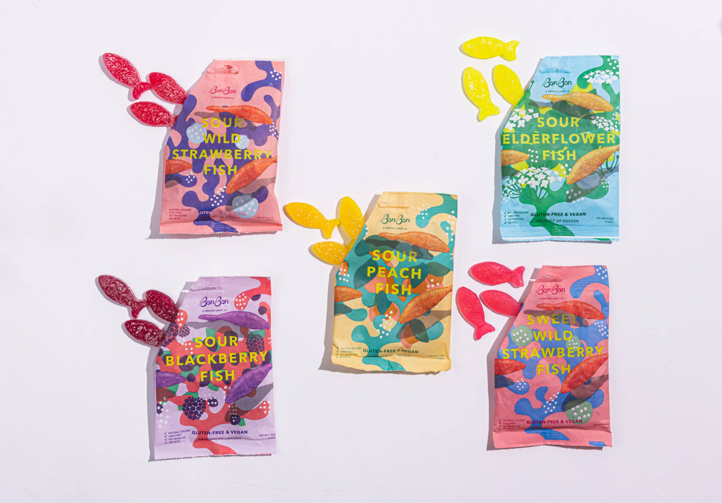 Colorful packages of sweet or sour fish-shaped swedish candies on a white background