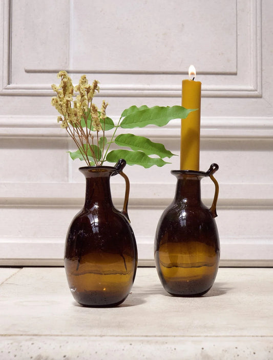 Two brown vases with a candle and plant on a light background