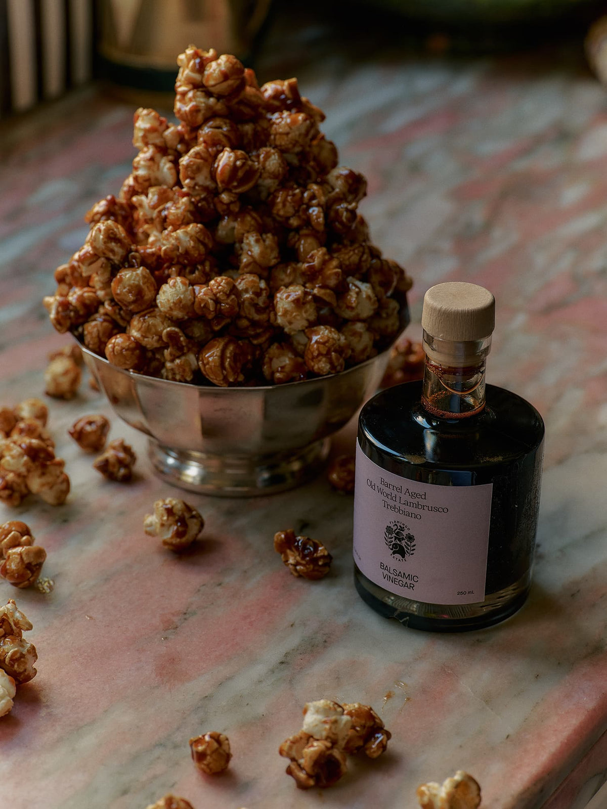Bowl of popcorn and a bottle of balsamic vinegar from Flamingo Estate on a textured surface