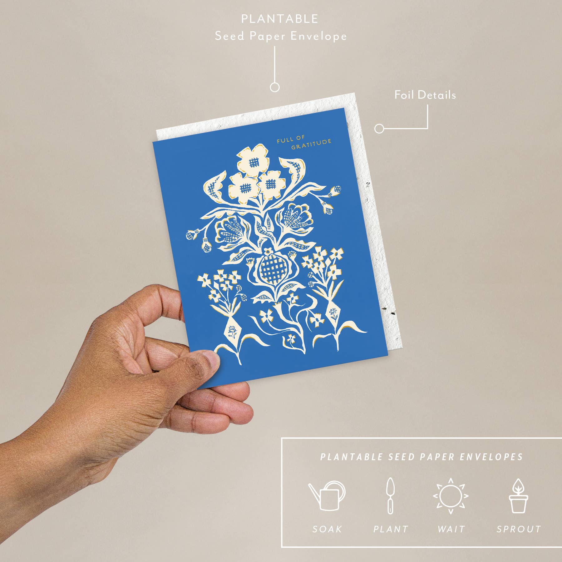 A hand holding a blue greeting card with a white floral pattern and text that reads 'FULL OF GRATITUDE', accompanied by a plantable seed paper envelope with eco-friendly packaging details.