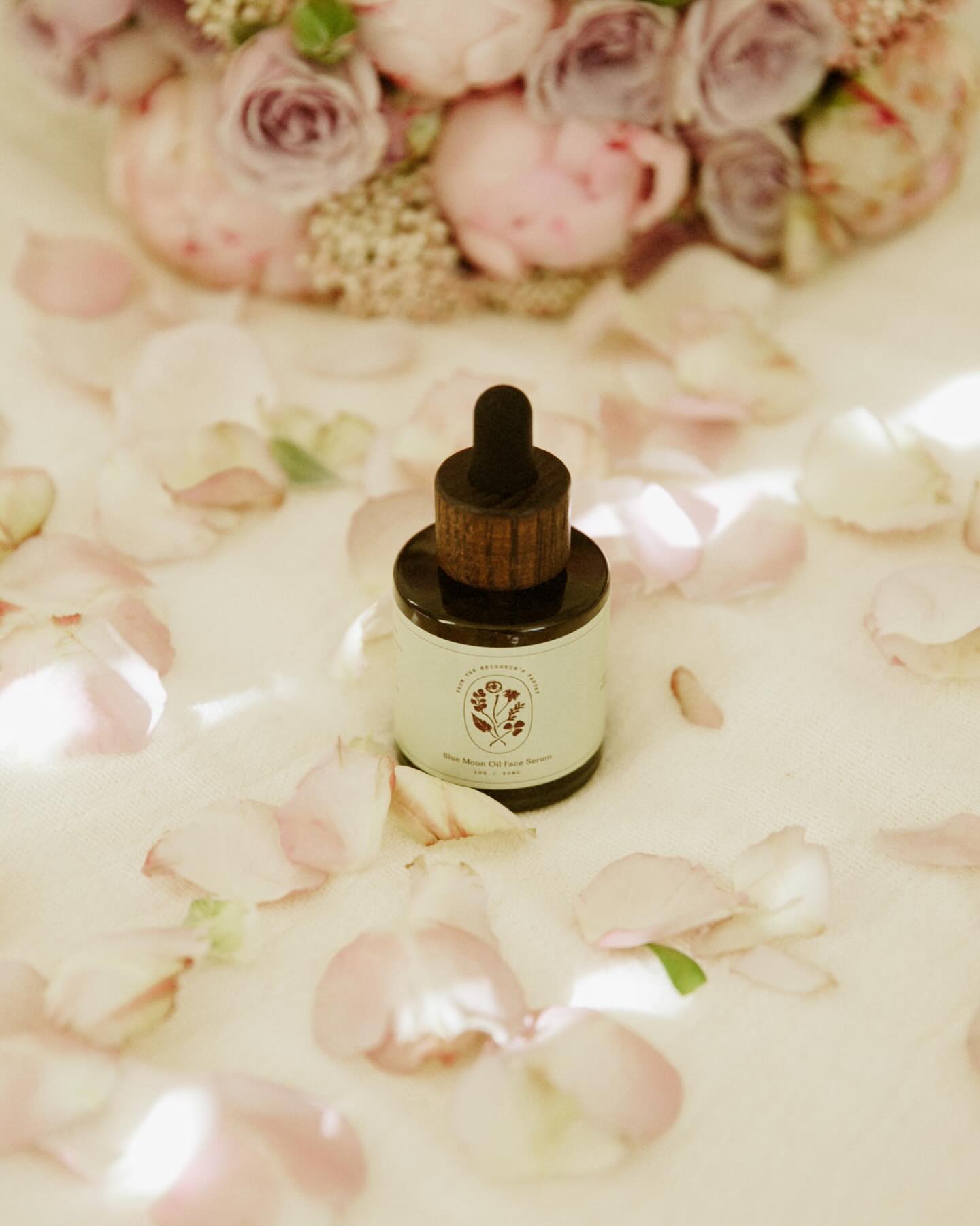 Skincare serum bottle from My Neighbor's with dropper on a bed of pink flowers