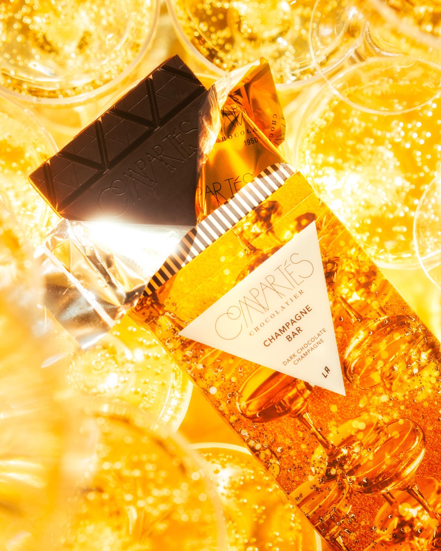 Gourmet Champagne Dark Chocolate Bar from Compartes surrounded by gold liquid and glistening crystals.