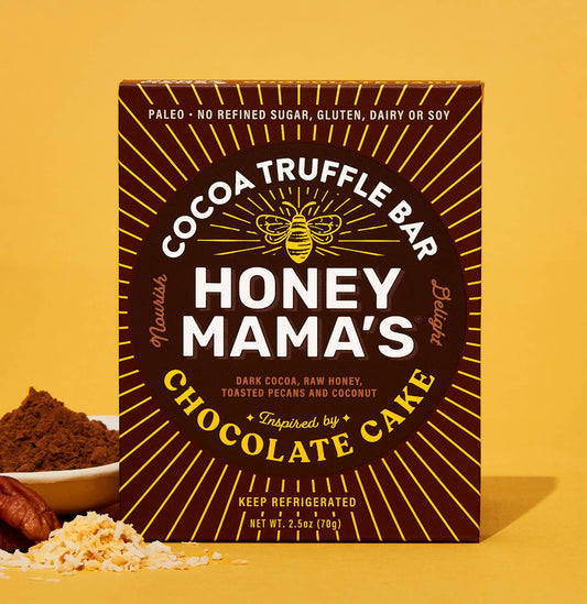 Packaging of Honey Mama's Chocolate Cake Cocoa Truffle Bar, featuring the product name, a brief description, and a list of dietary preferences such as paleo, refined sugar-free, dairy-free, and gluten-free. Made with real foods.