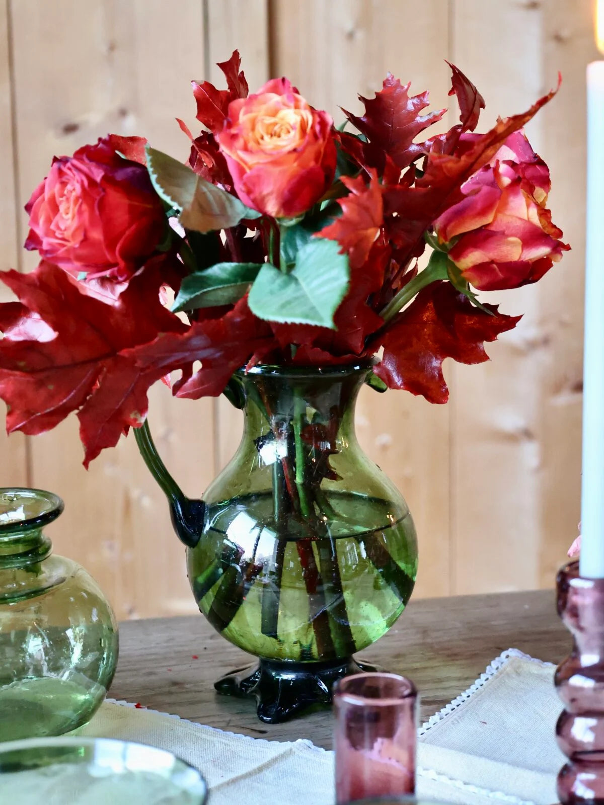 Bouquet of red flowers in a elegant green vase on a table with a wooden background