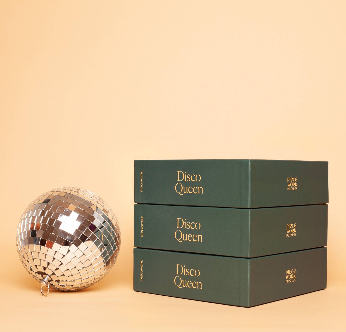3 Disco Queen 500-piece puzzle boxes from Piecework Puzzles, with a disco ball nearby.
