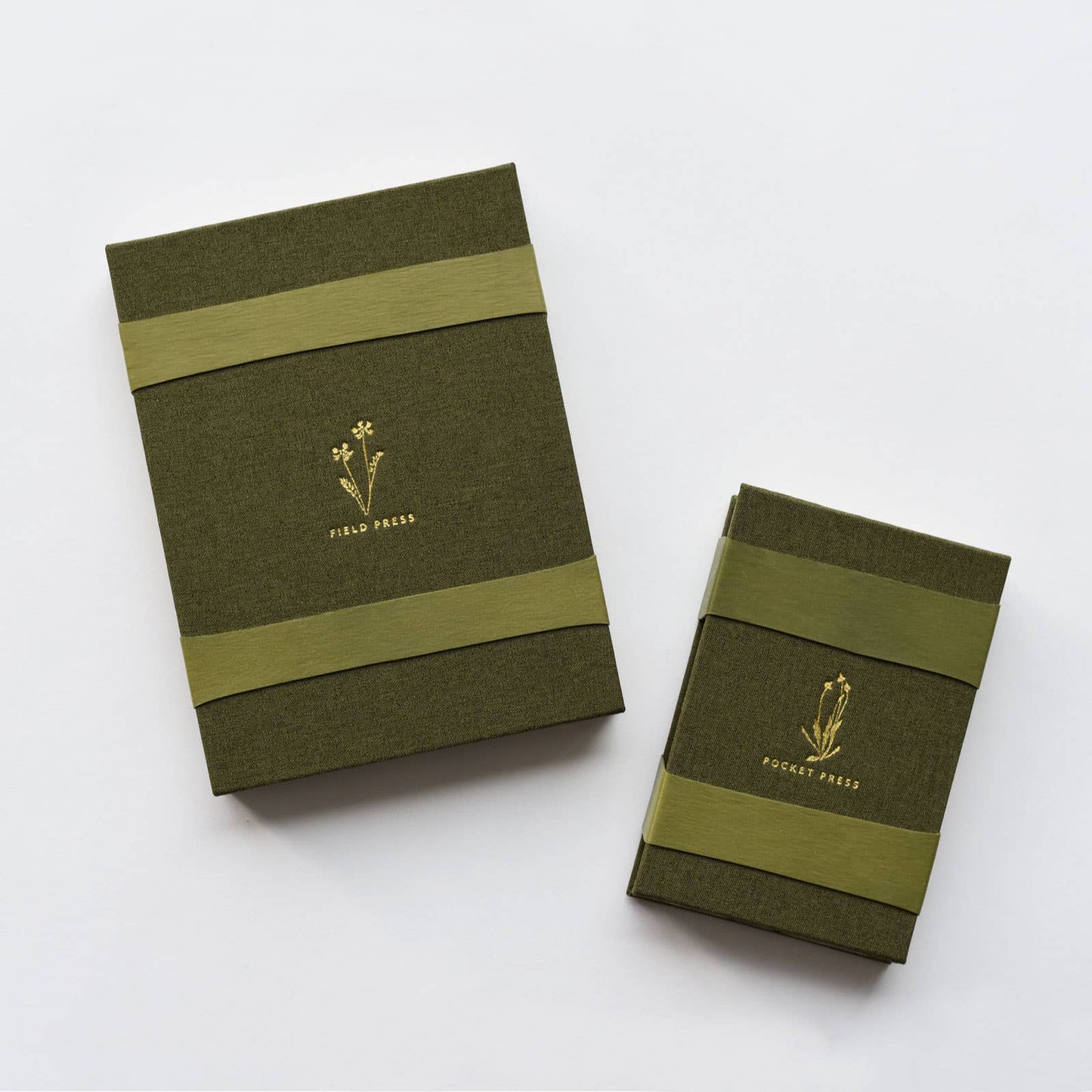 Two green linen-covered field flower press with gold foil details and two heavyweight bands each, by June & December. 