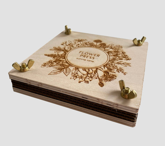Wooden flower press kit with brass hardware and floral design in a natural wood color.