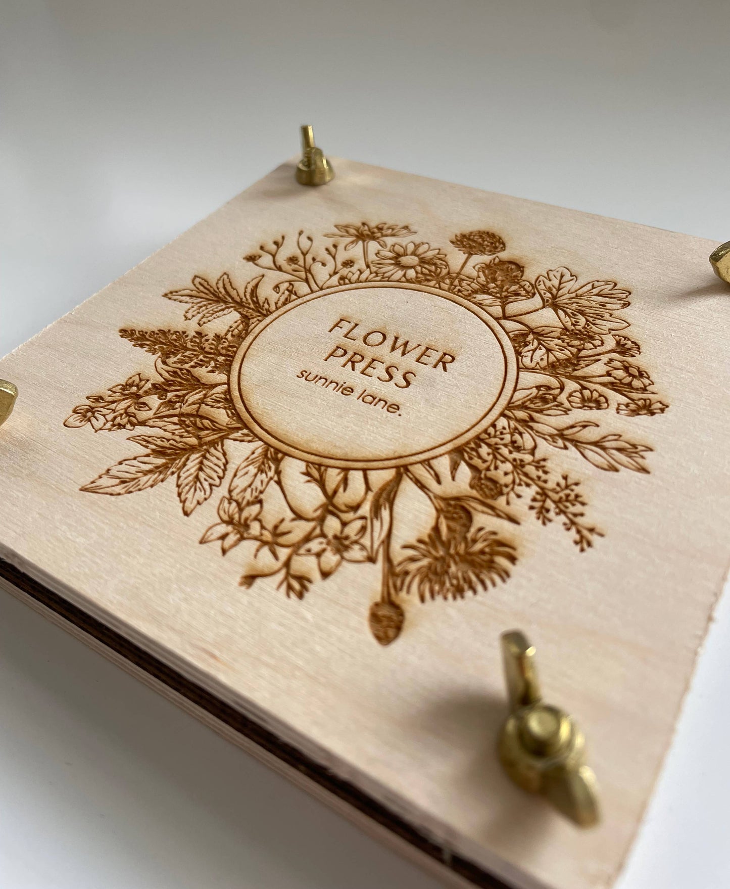 Compact floral press displayed on tabletop with brass hardware