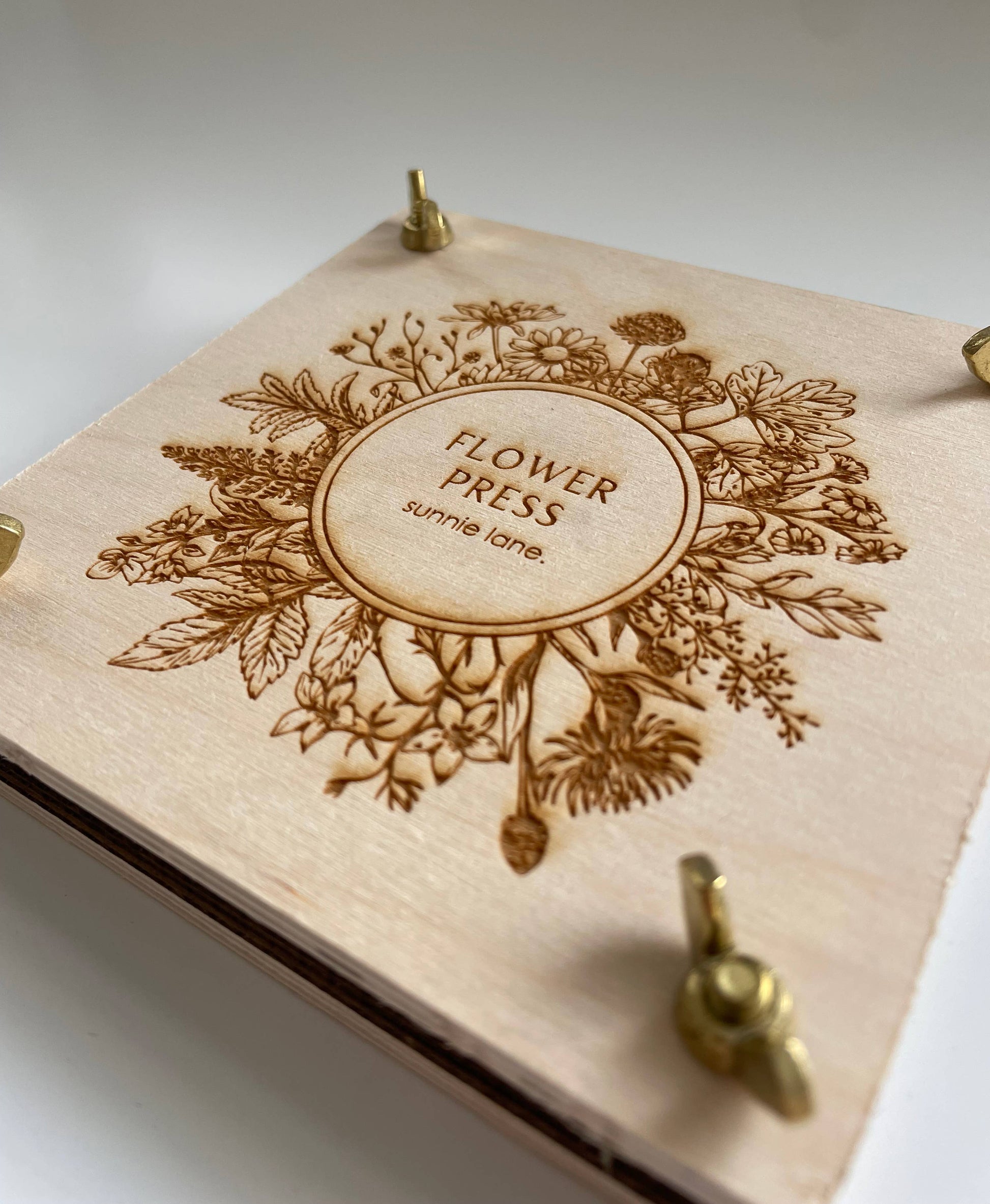 Compact floral press displayed on tabletop with brass hardware