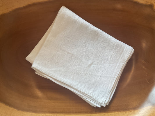 Stack of white linen hand towels on a wooden surface