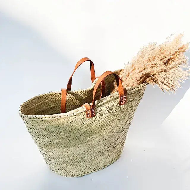 natural woven basket for beach, market, or daily use, with leather handles on a light background