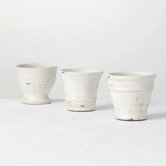Three small white glazed ceramic pots with elegant details.
