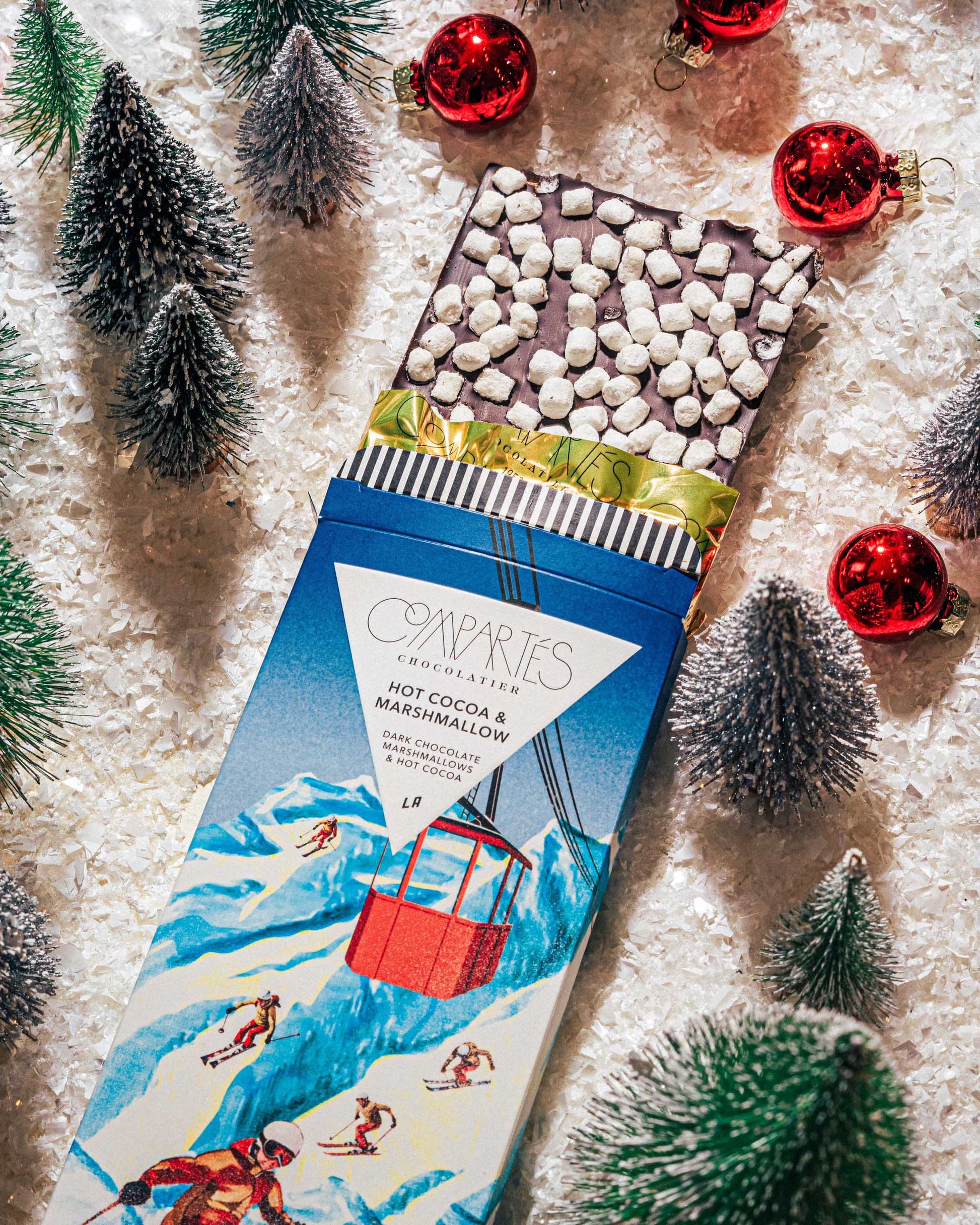 Hot Cocoa Marshmallow dark chocolate packaging with Christmas decorations on a snowy background