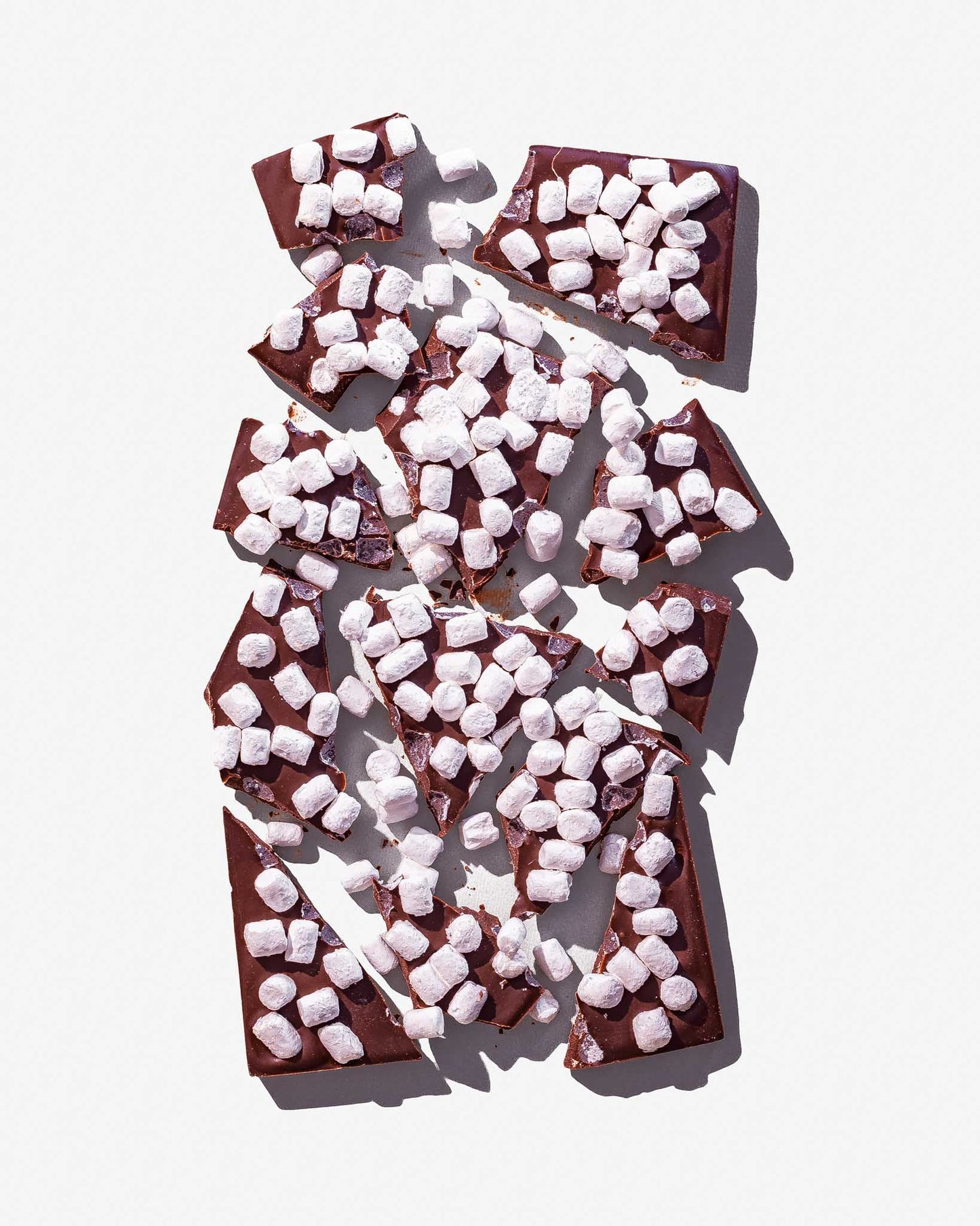 Hot Cocoa and Marshmallow Chocolate bar broken into chunks on a white background