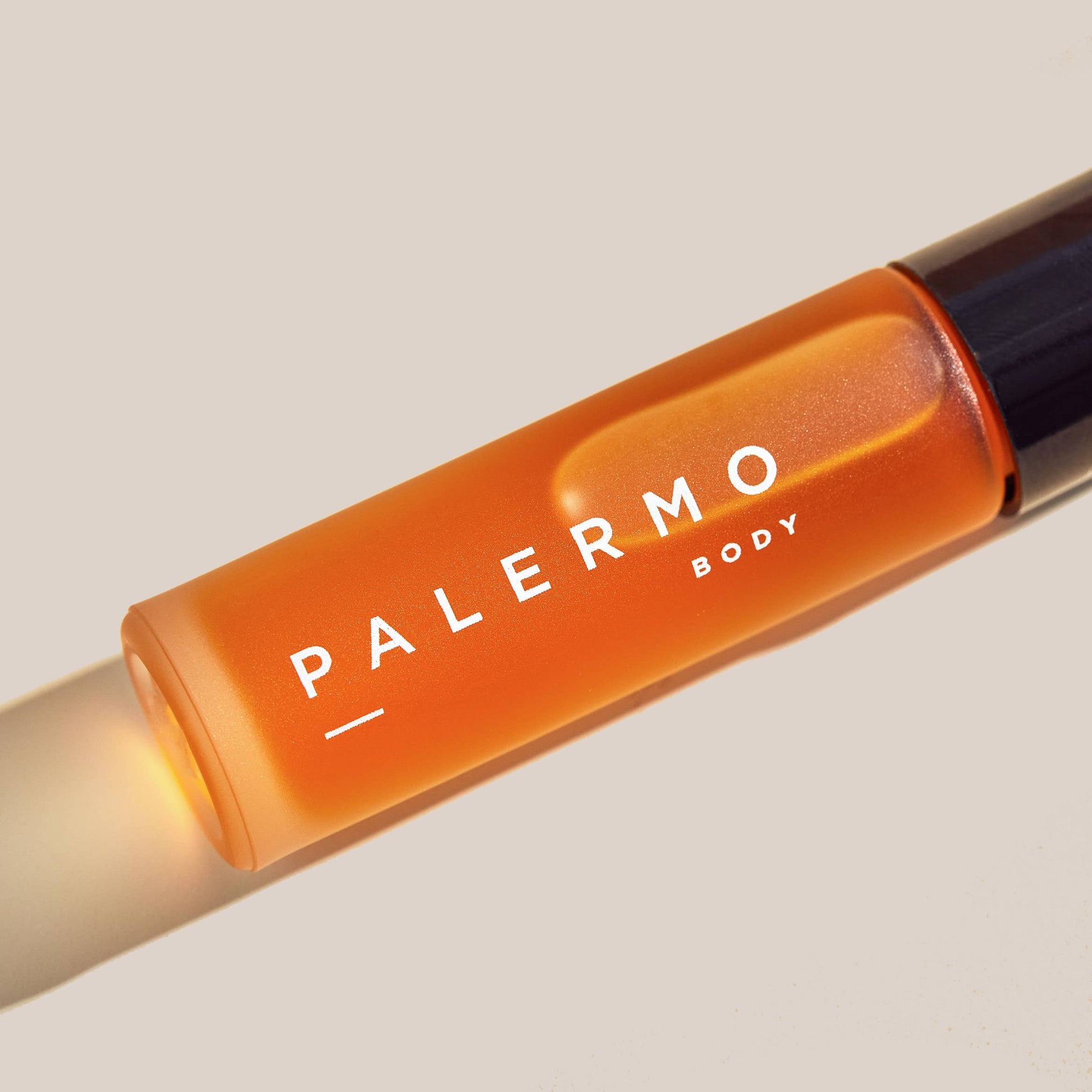 Orange bottle of Palermo Body floral and earthy aromatherapy roll-on on a beige background