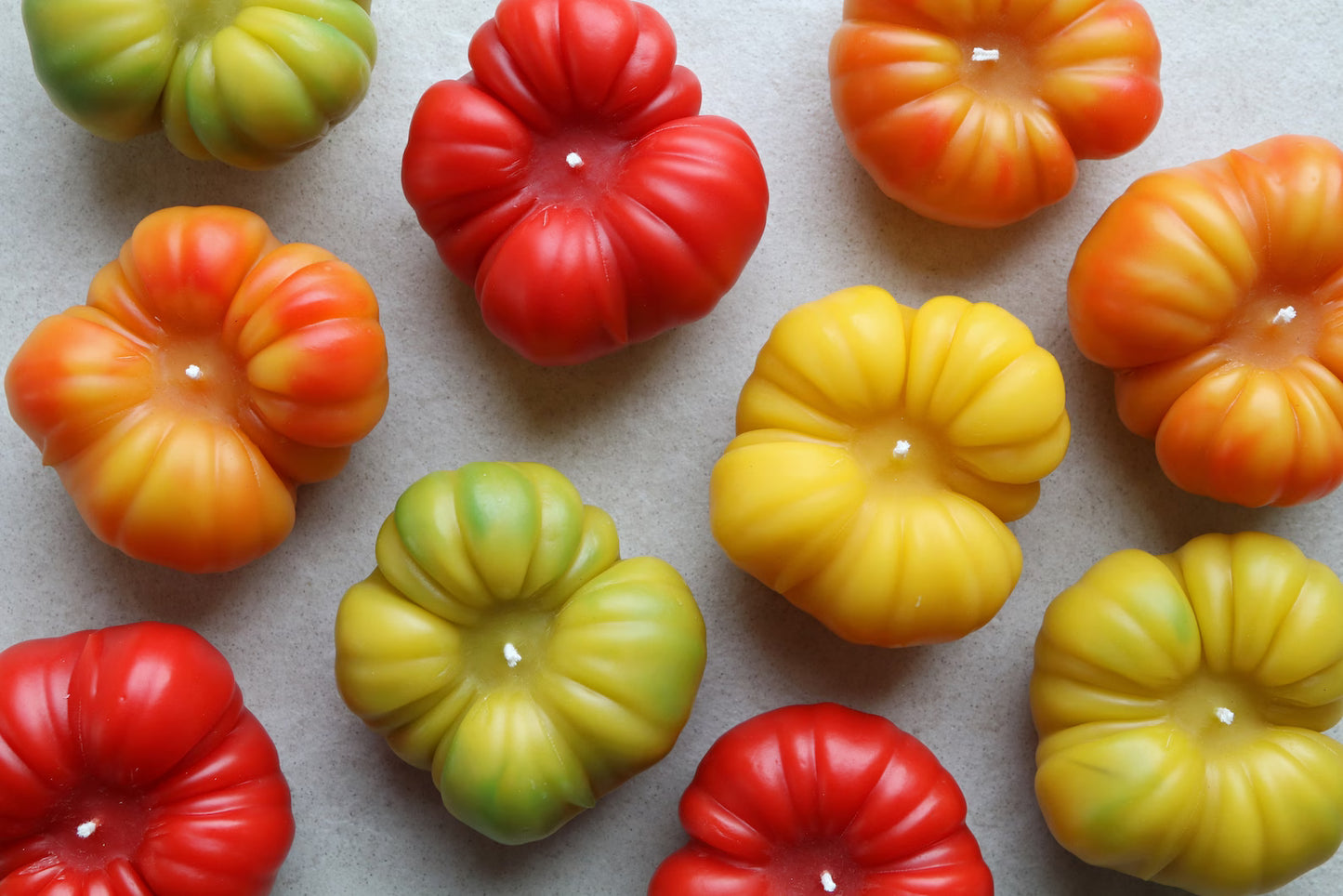 Handmade heirloom tomato beeswax candles in various colors: red, orange, yellow and green.