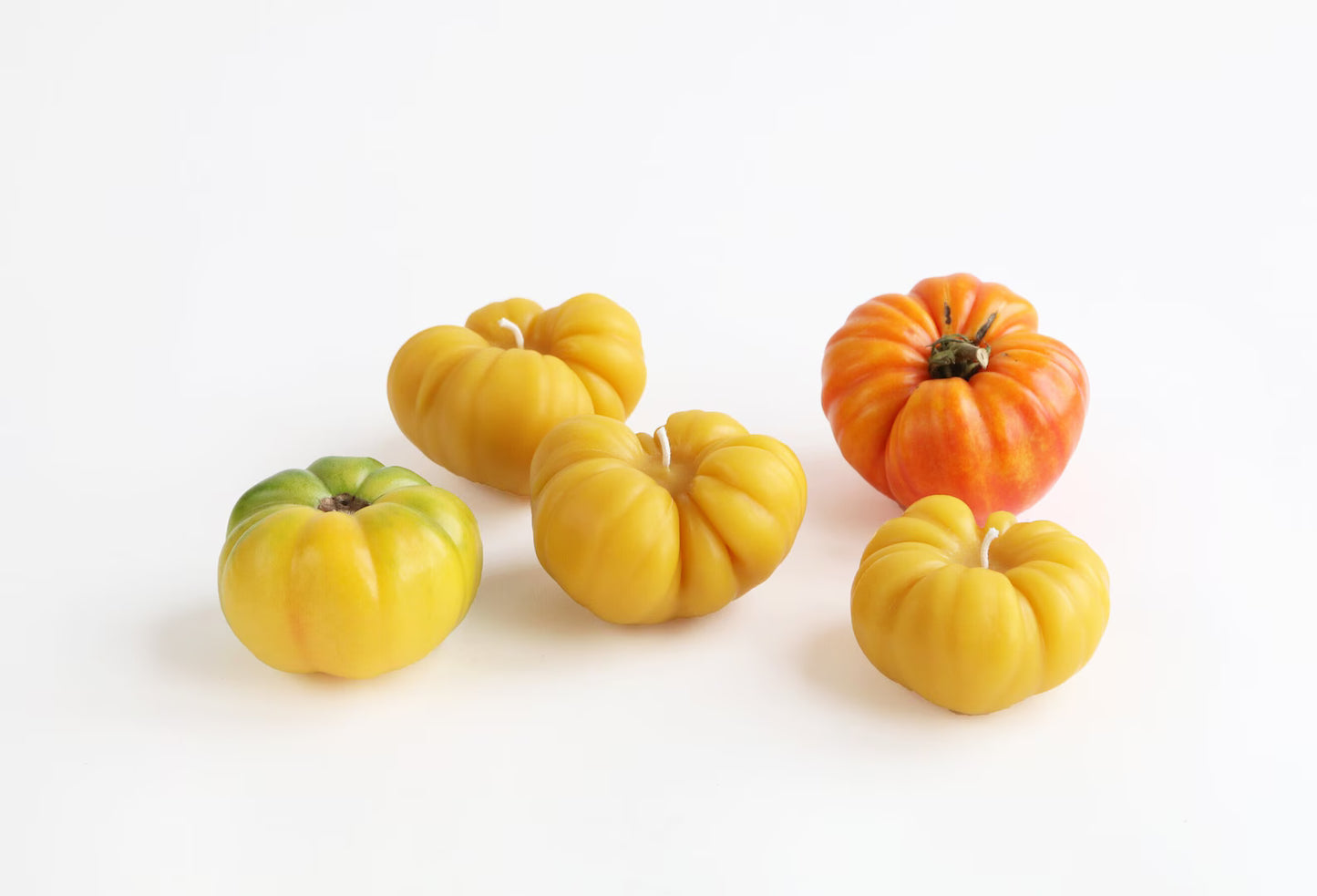 handmade heirloom tomato beeswax candles in yellow, next to real tomatoes