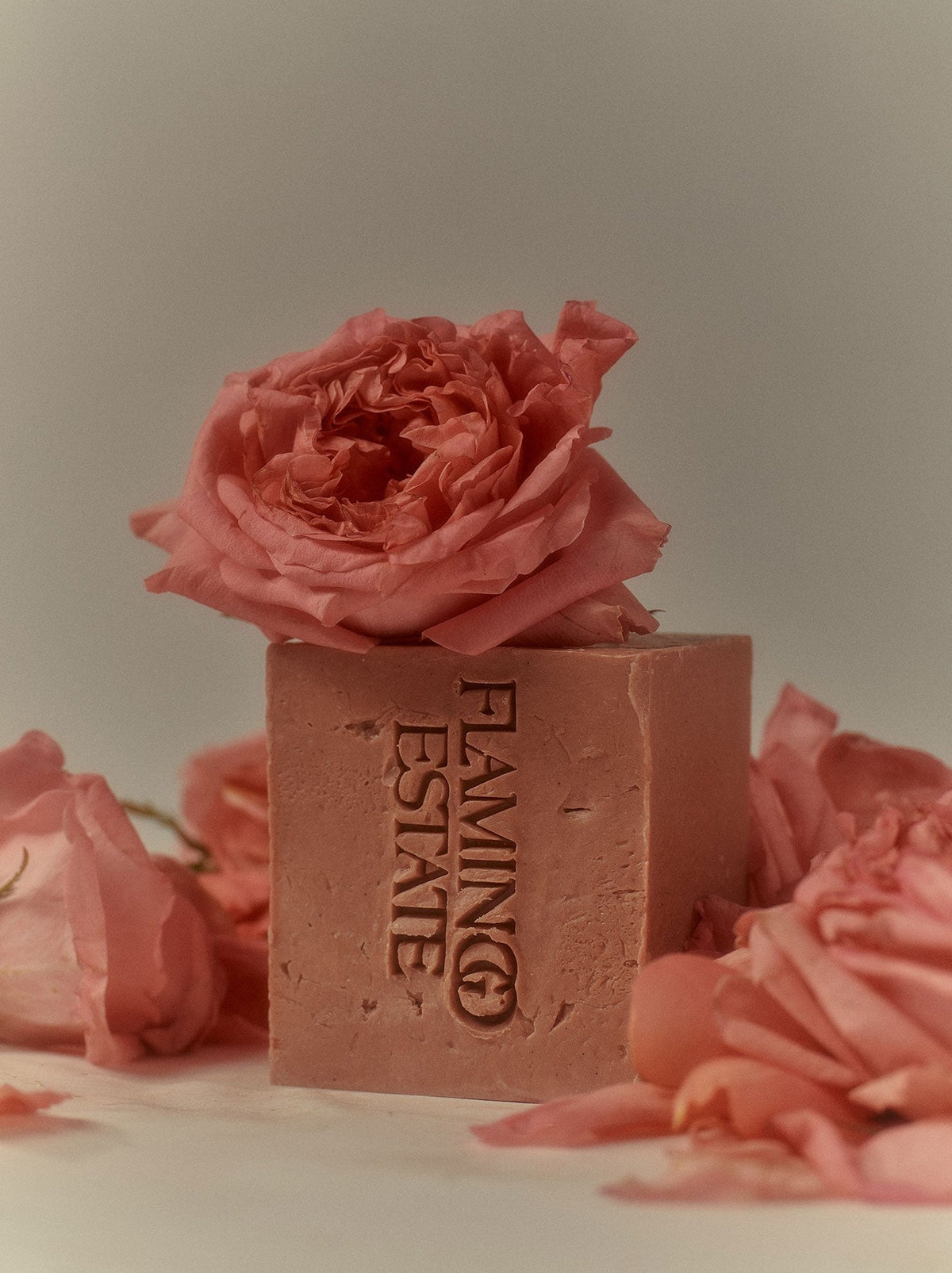 Bar of soap with 'Flamingo Estate' branding surrounded by pink roses on a light background