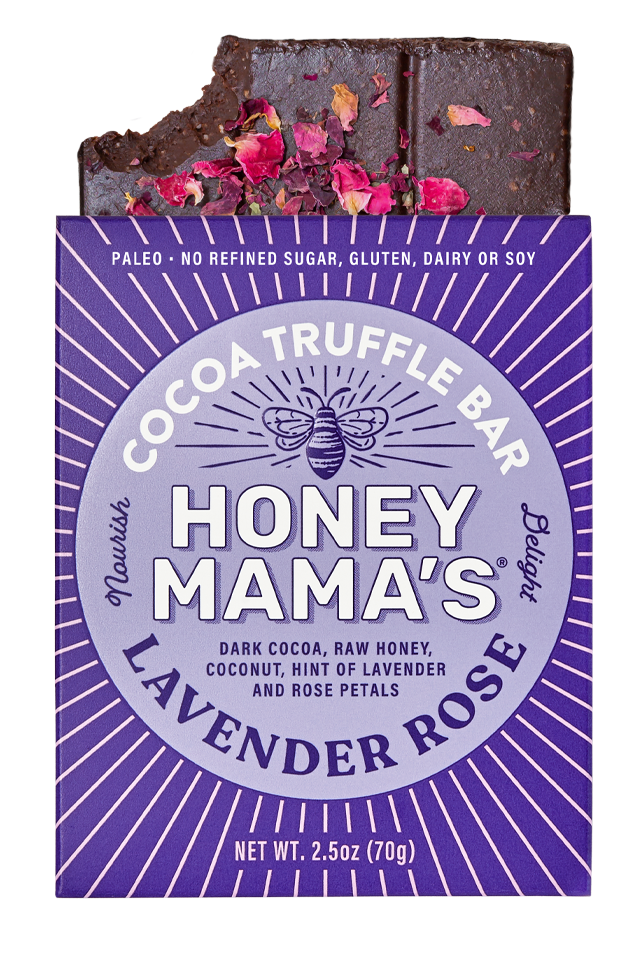 Packaging of Honey Mama's Lavender Rose Cocoa Truffle Bar with the product visible, topped with red rose petals. On the packaging we can see that the bar is made from real foods only, paleo, refined sugar-free, dairy-free, and gluten-free.