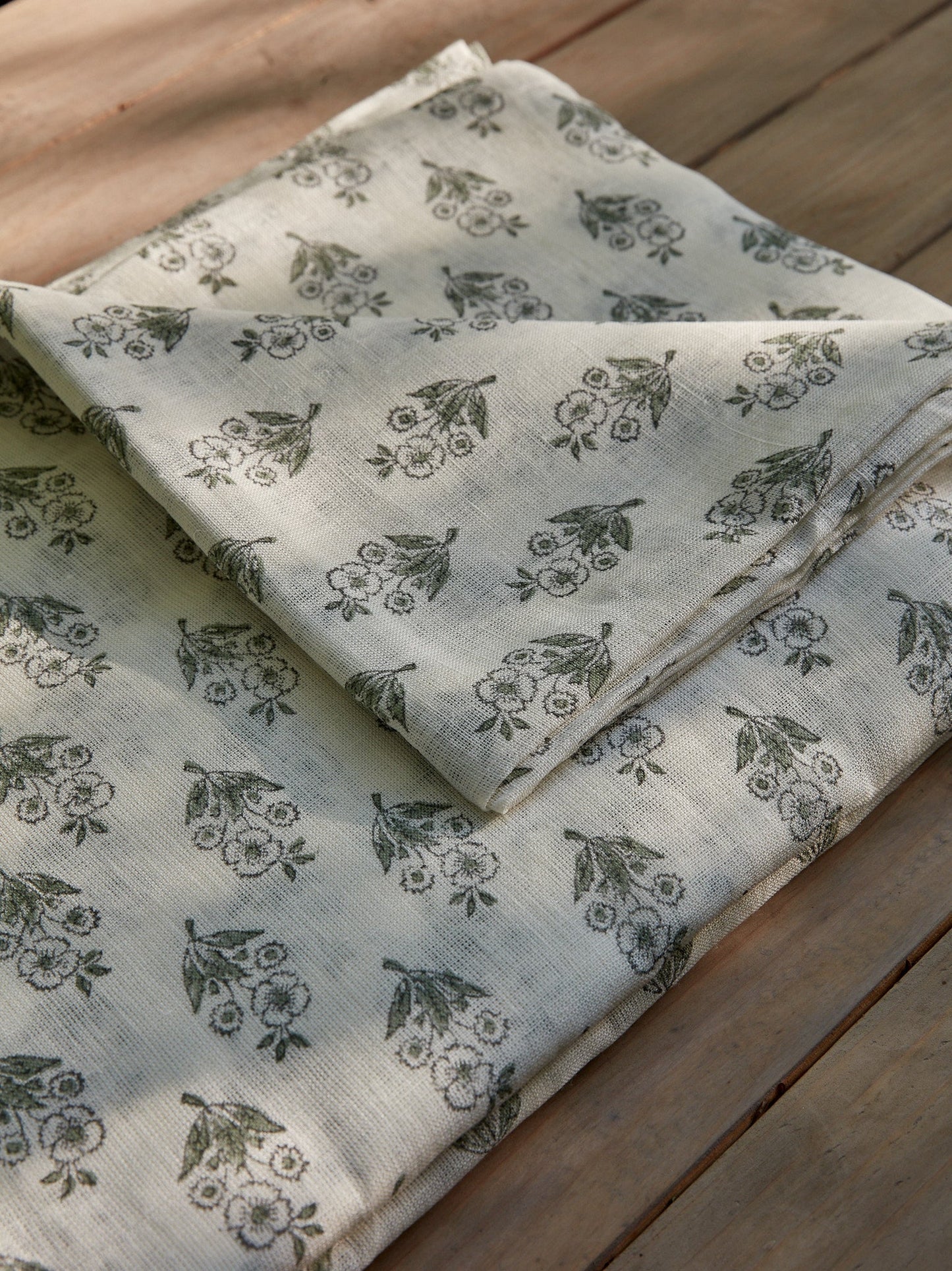 Folded linen fabric with floral pattern on a wooden surface