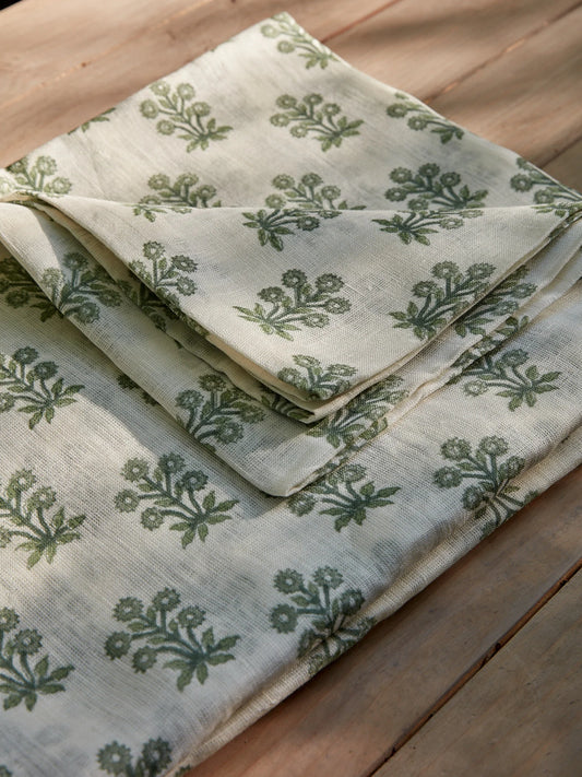 Folded linen fabric with green floral pattern on a wooden surface