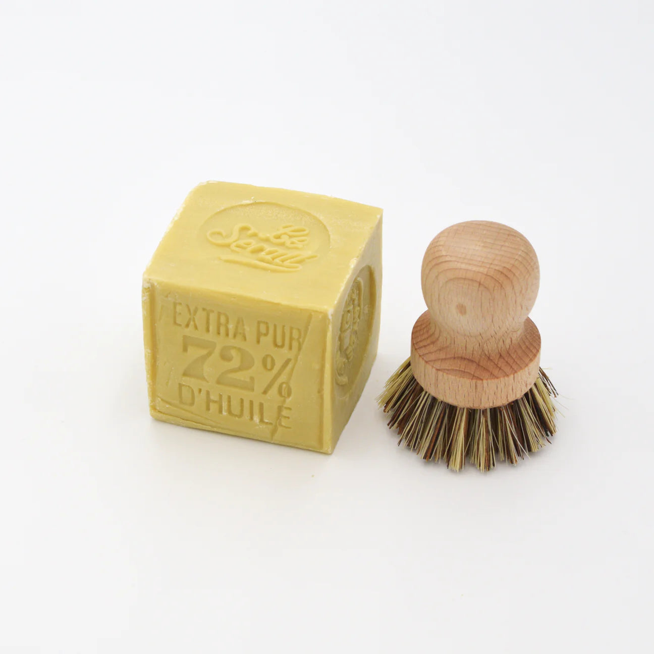 Bar of Marseille soap and wooden brush on a white background