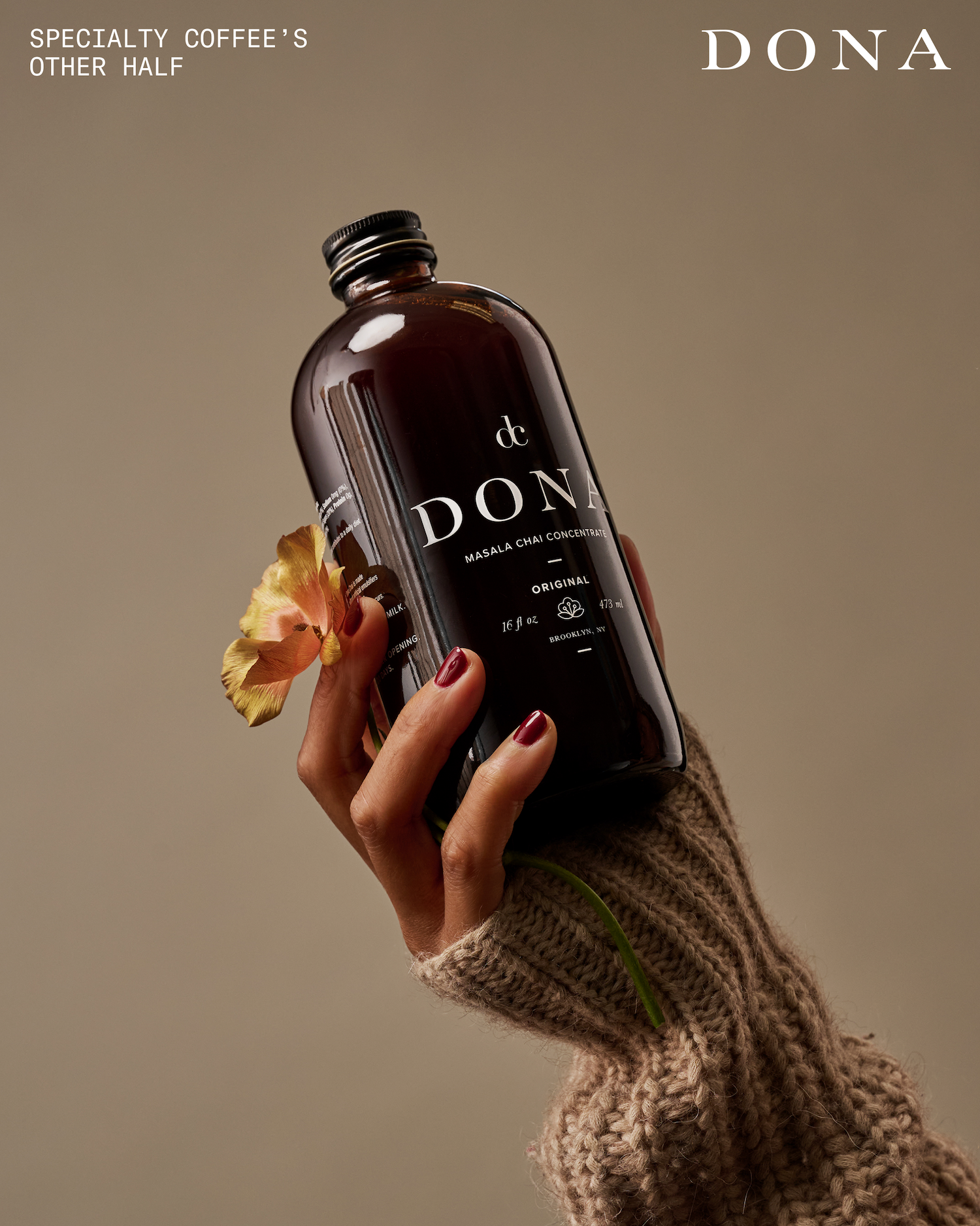 A hand holding a bottle of Masala Chai Concentrate from the brand Dona