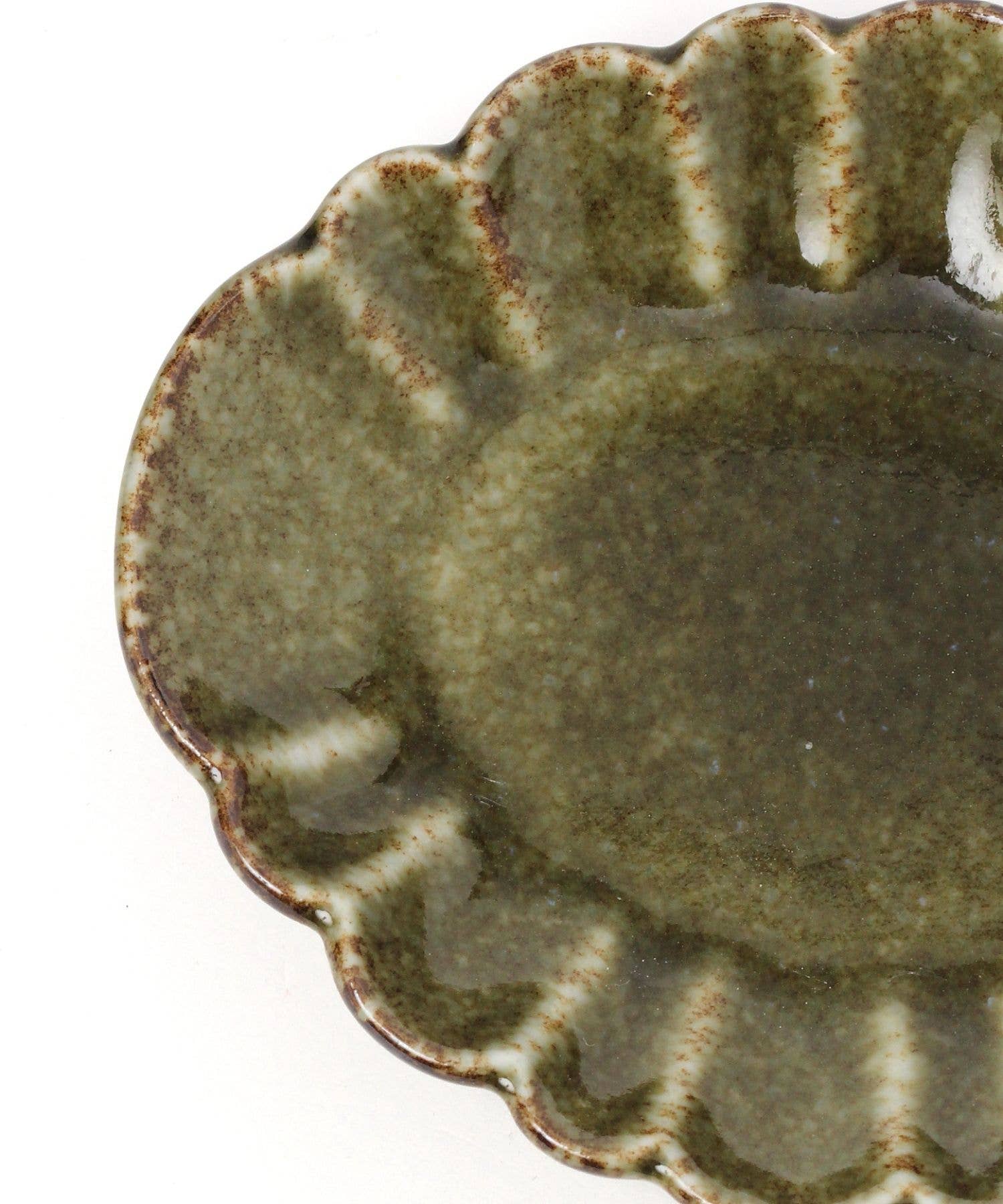 Close-up on a mini oval chrysanthemum-shaped ceramic plate with a green tint and floral detailing on the rim.