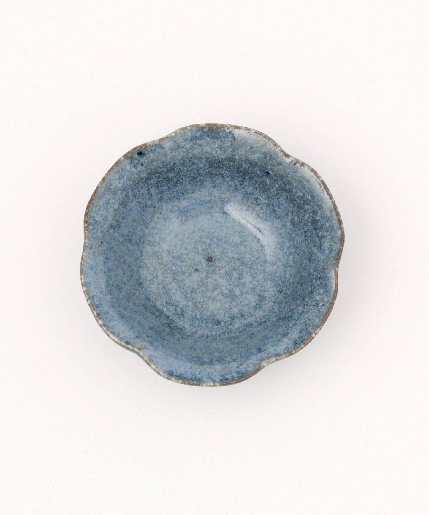 A ceramic mino ware mini bowl with a flower shape and a soft blue speckled glazed finishe on a white background.