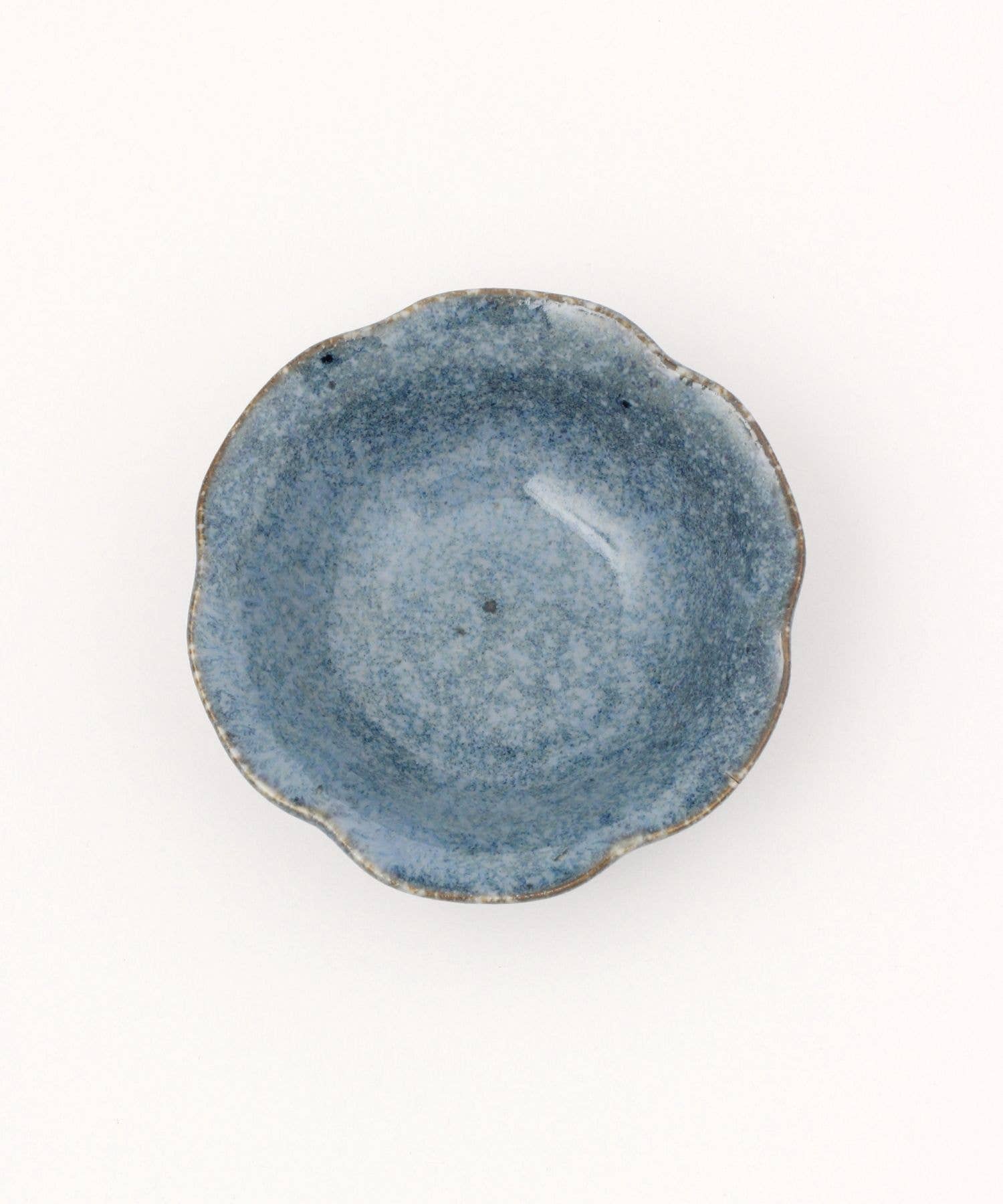 A ceramic mino ware mini bowl with a flower shape and a soft blue speckled glazed finishe on a white background.