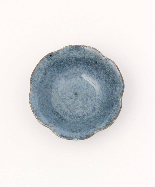 A ceramic mino ware mini bowl with a flower shape and a soft blue speckled glazed finishe on a white background.