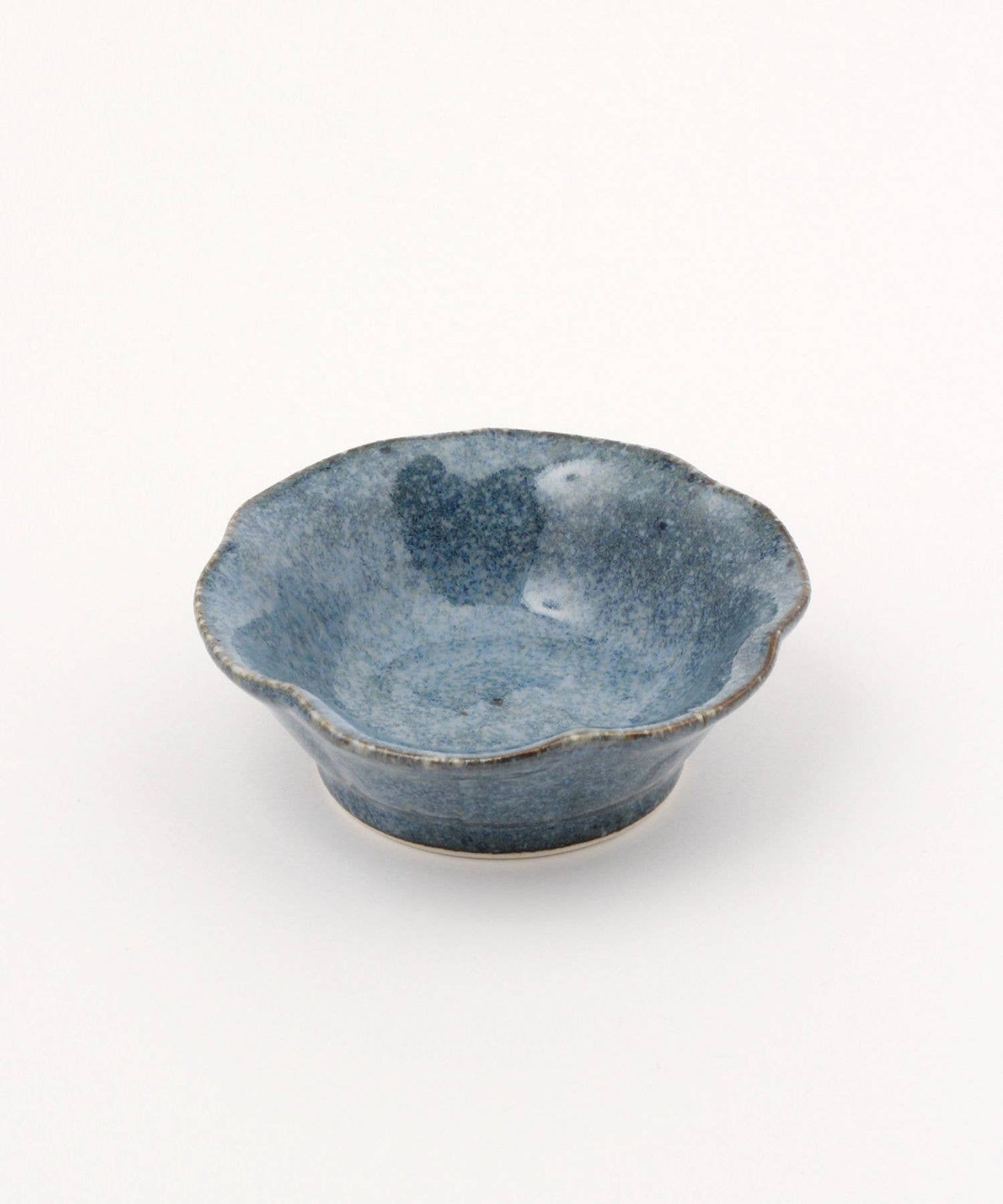A ceramic mino ware mini bowl with a flower shape and a soft blue speckled glazed finishe, seen from the side on a white background.