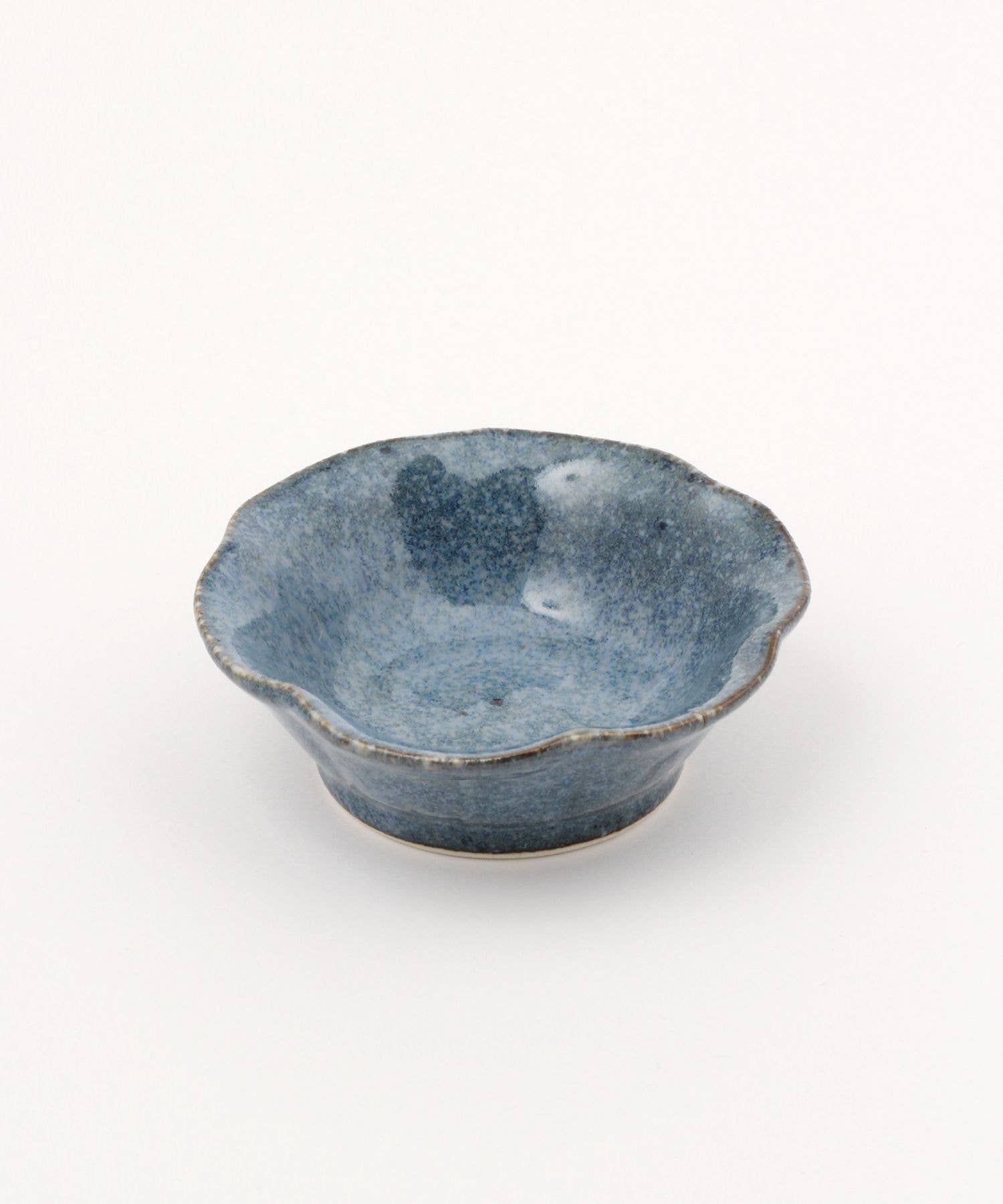 A ceramic mino ware mini bowl with a flower shape and a soft blue speckled glazed finishe, seen from the side on a white background.
