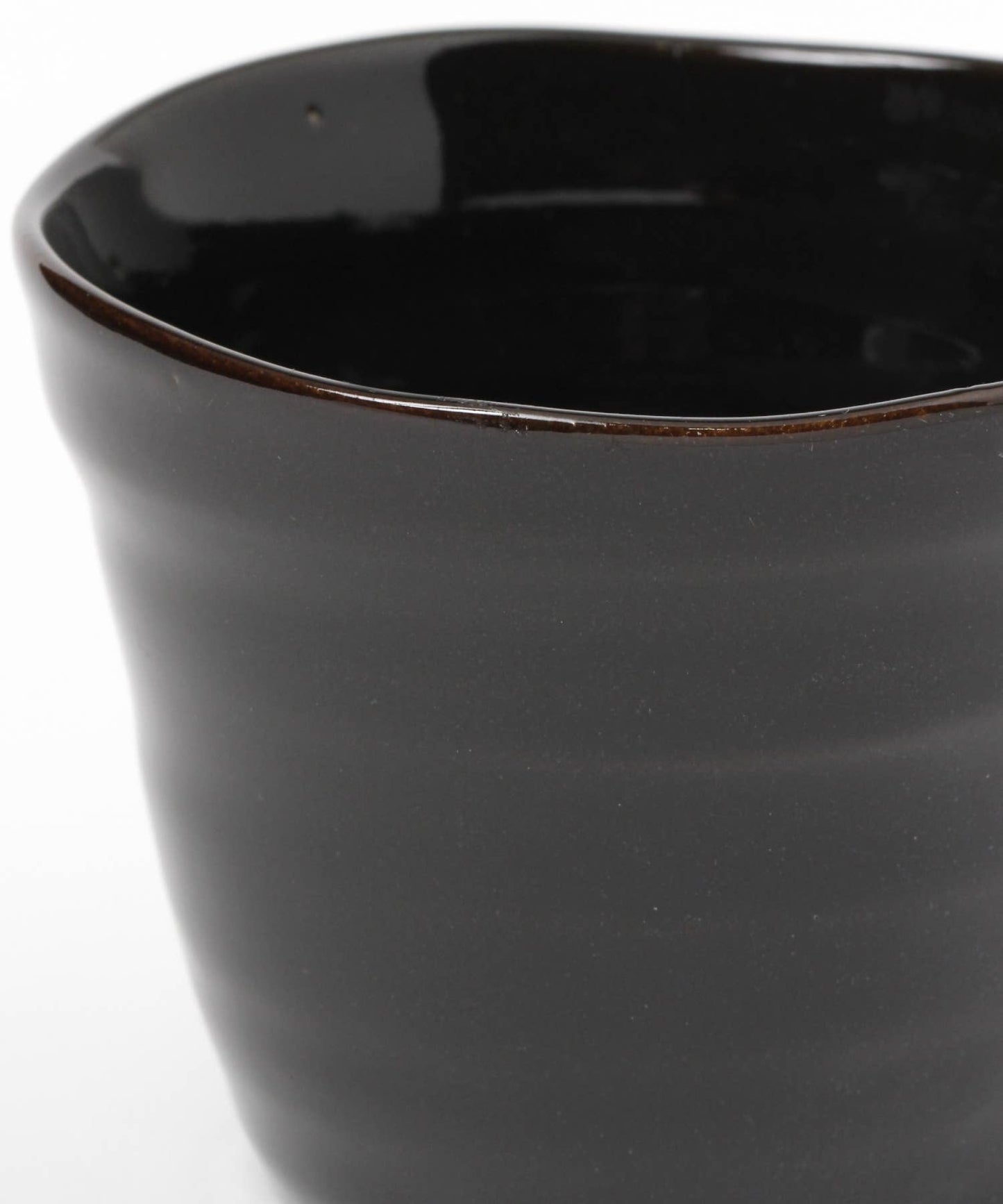 Close-up on a gloss black ceramic mino ware mug with an organic shape on a white background.