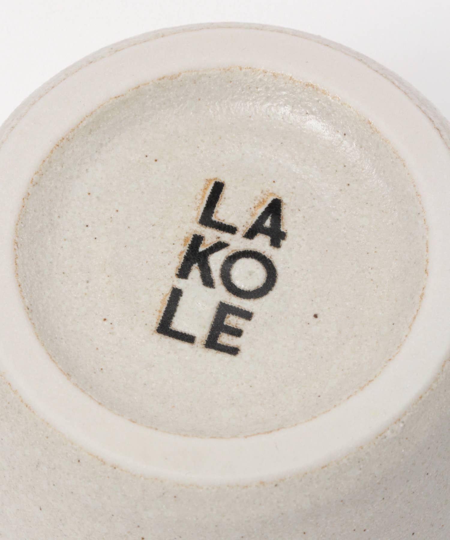 A white ceramic mino ware mug with an organic shape, seen from the bottom, on a white background. We can read "Lakole", which is the brand.