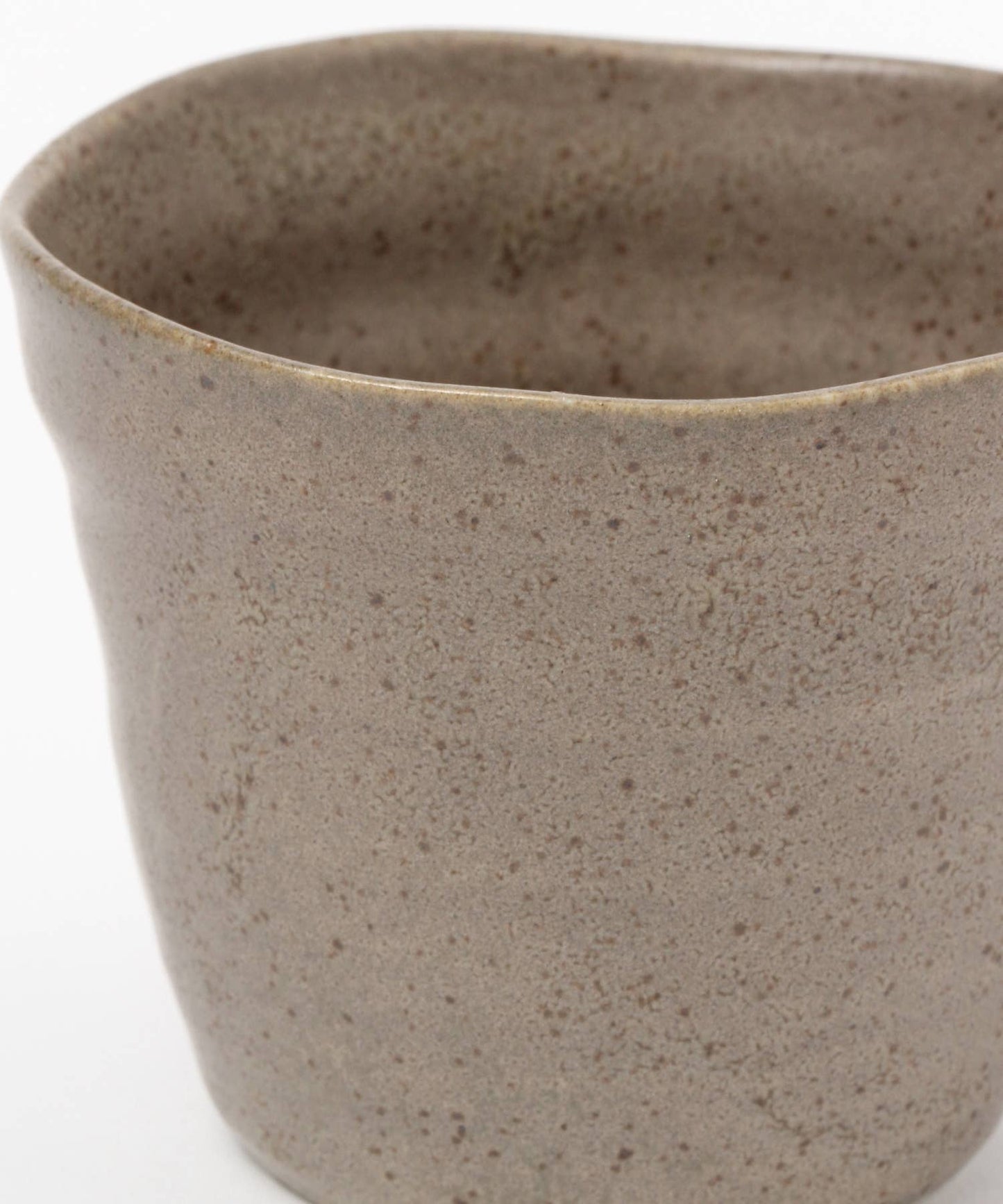 Close-up on a beige ceramic mino ware mug with an organic shape on a white background.