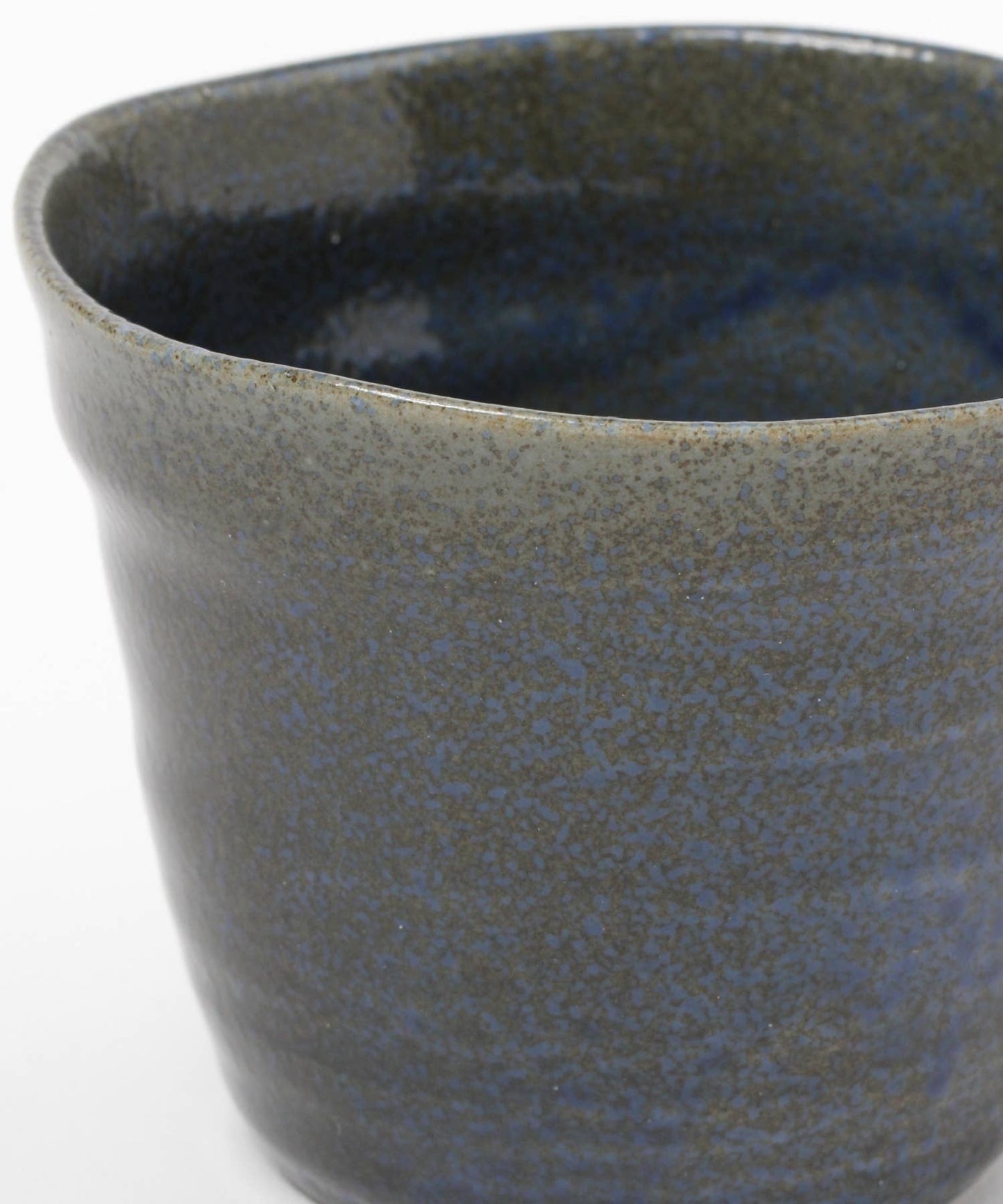 Close-up on a dark blue ceramic mino ware mug with an organic shape on a white background.