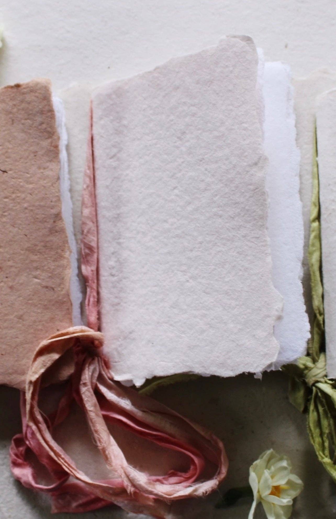 A handmade blush notebook with a pink silk ribbon and botanical-dyed cover.