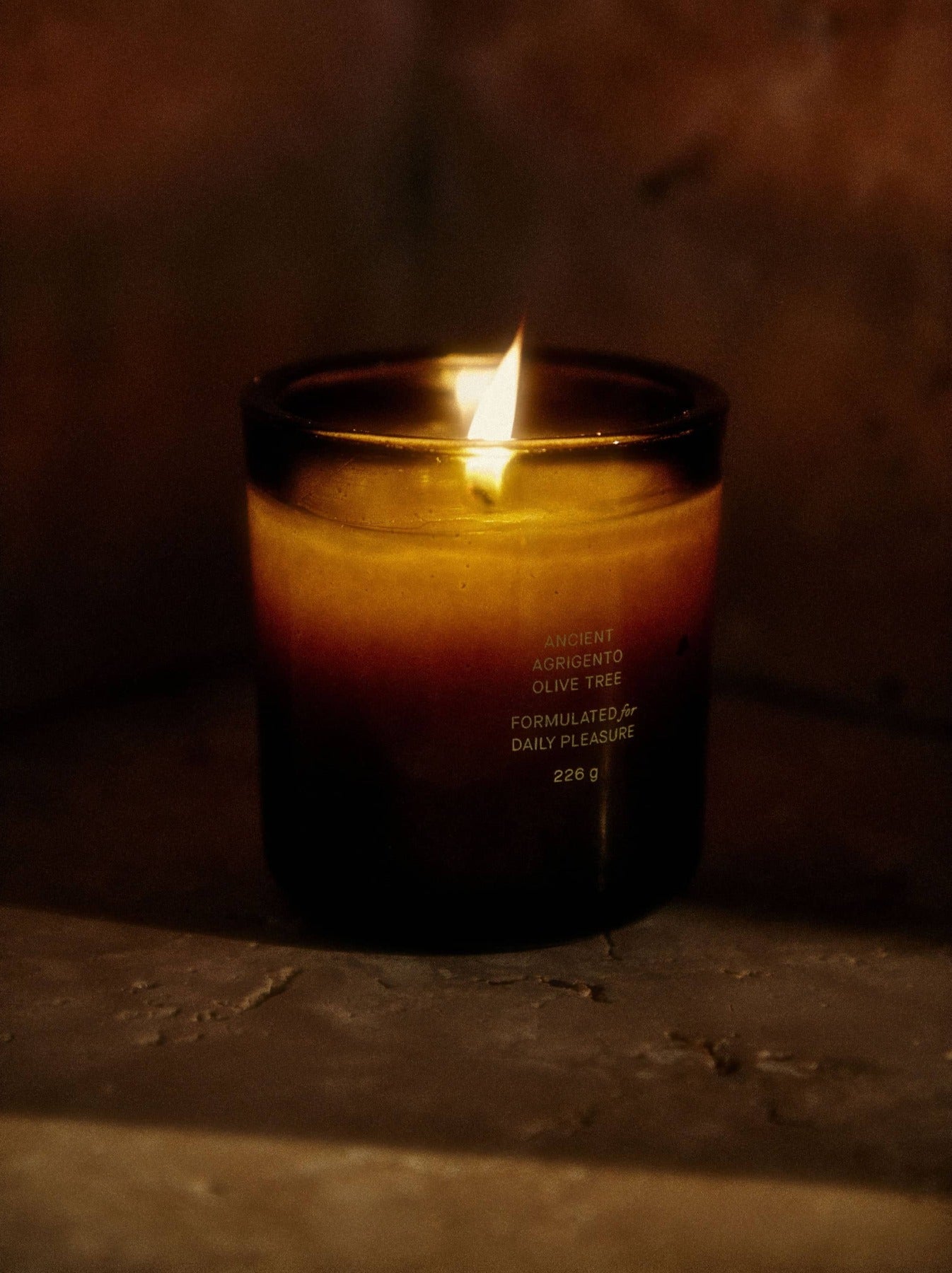 Candle in a glass jar with a label on a textured surface