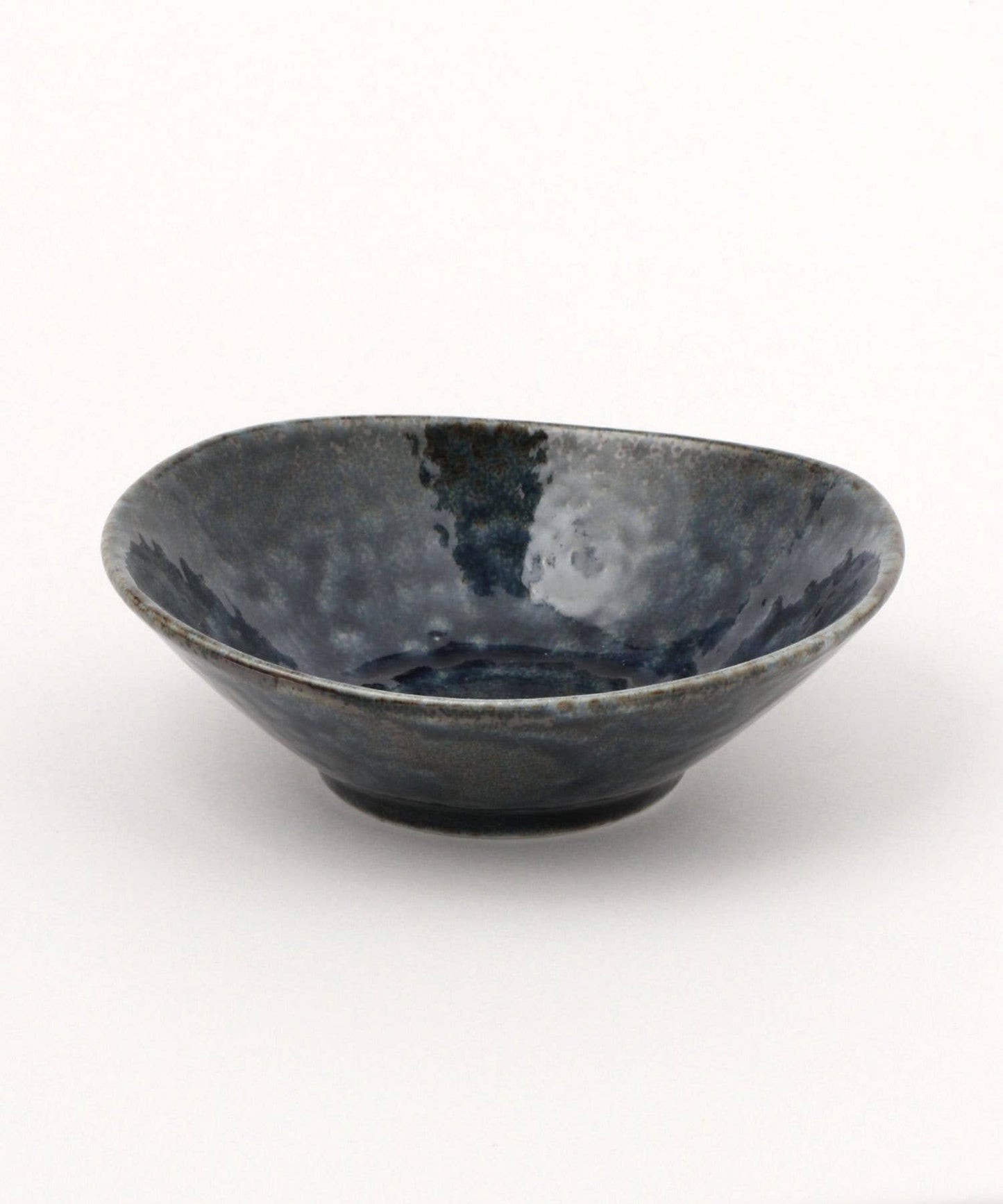 A dark blue ceramic mino ware mini bowl with an organic shape on a white background.