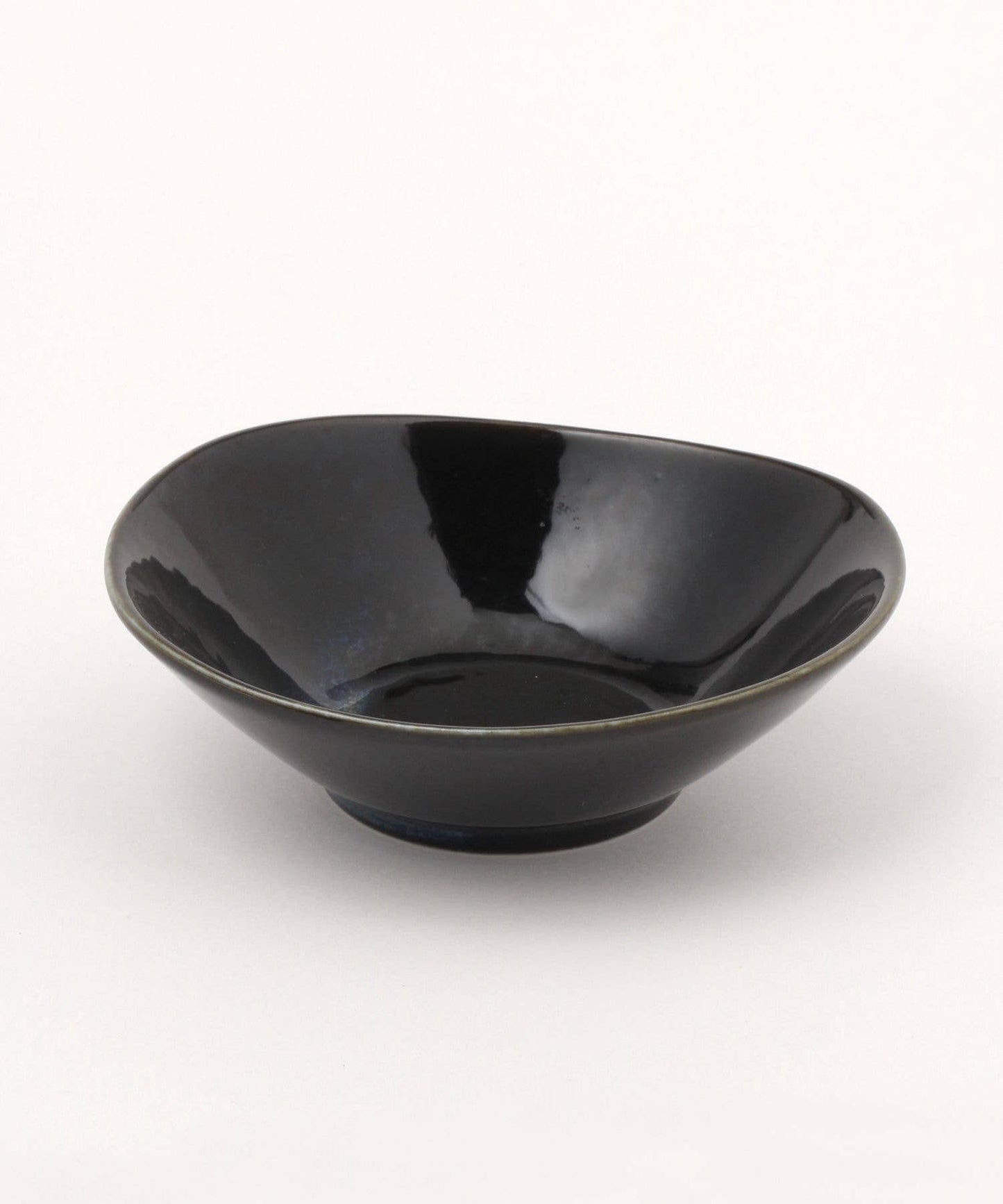 A gloss black ceramic mino ware mini bowl with an organic shape on a white background.