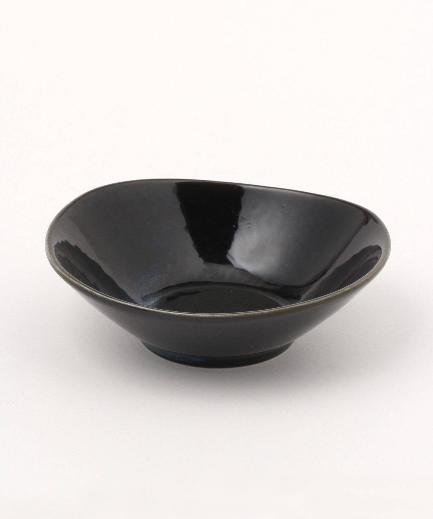 A gloss black ceramic mino ware mini bowl with an organic shape on a white background.