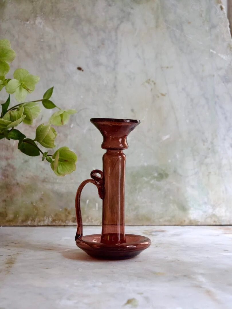 La Soufflerie Porta Candele with Handle Framboise (raspberry hue) glass candle holder on a marble surface with a green plant in the background