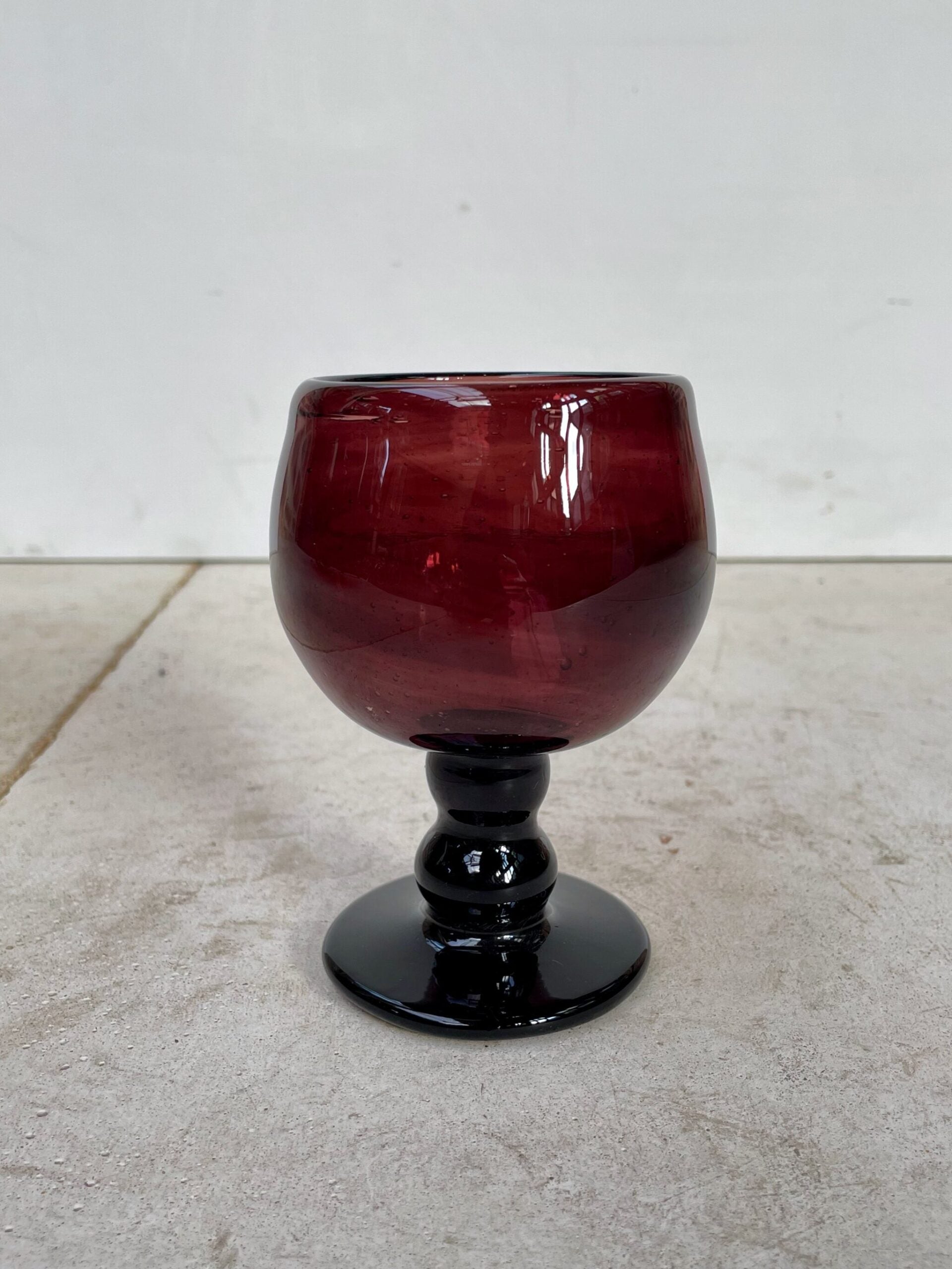 Red handmade wine glass on a light gray surface