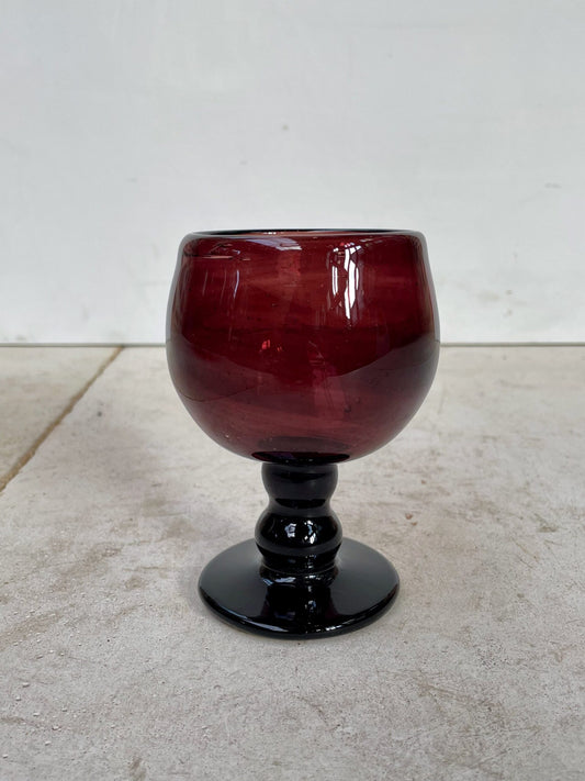 Red handmade wine glass on a light gray surface