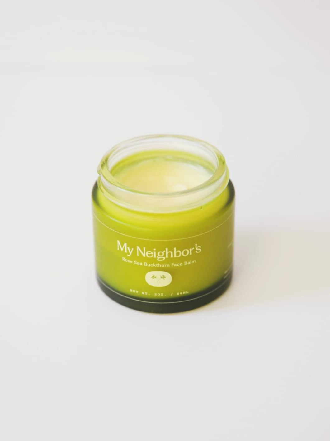 Green jar of 'My Neighbors' Rose and Sea buckthorn tallow balm on a white background