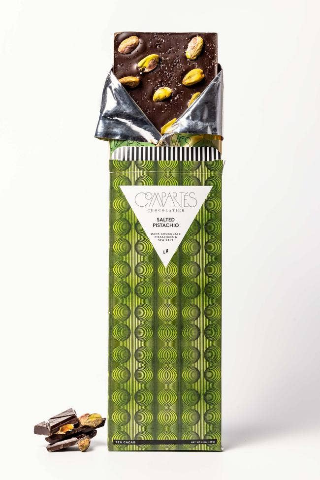 Chocolate bar with pistachios in a green packaging on a white background