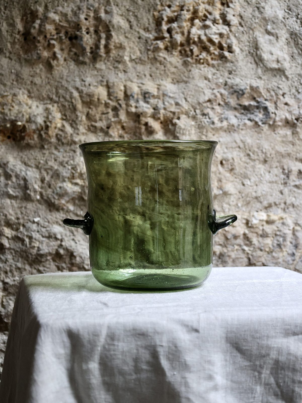 Green glass champagne bucket on a stone surface with a textured background